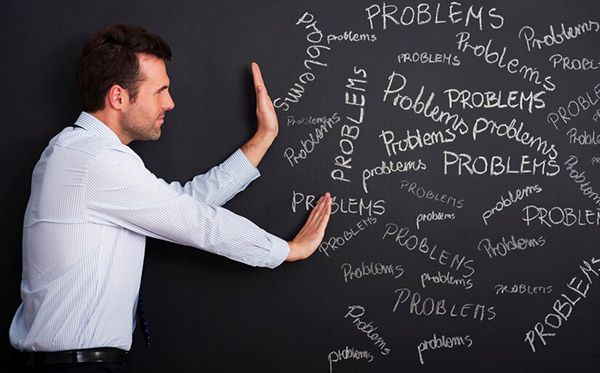 A man is standing in front of a blackboard with problems written on it