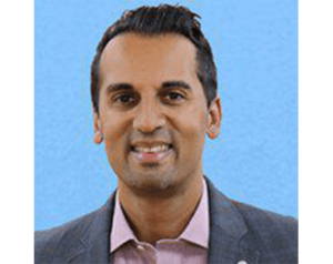 A man in a suit and pink shirt is smiling for the camera.