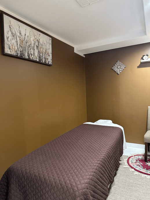 A room with a bed , chair and a painting on the wall.