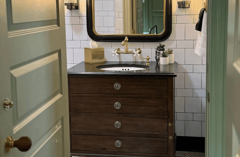 Bathroom vanity with dark wood cabinet, white tile walls, and a mirror between mint-green doors