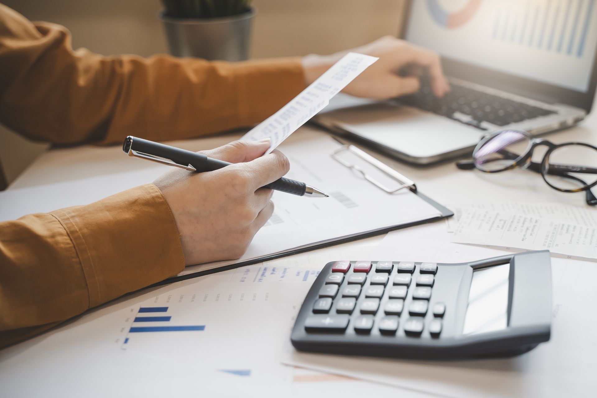 A person is sitting at a desk using a laptop and a calculator.