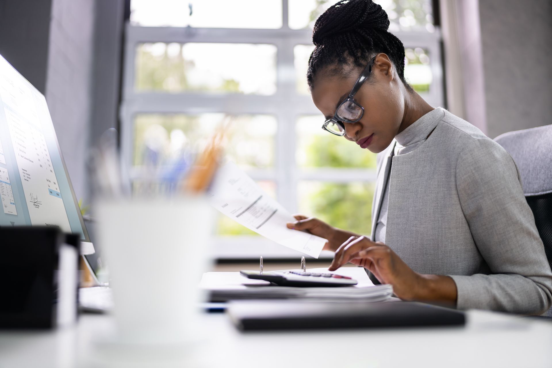 A woman is sitting at a desk looking at a piece of paper.