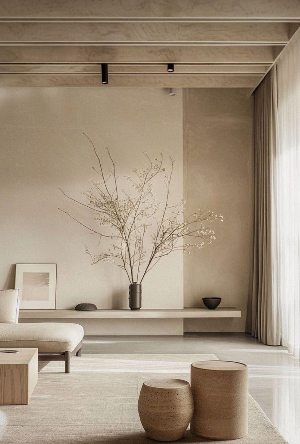 Een woonkamer in neutrale tinten met een plank, een vaas met takken en twee gevlochten krukjes.