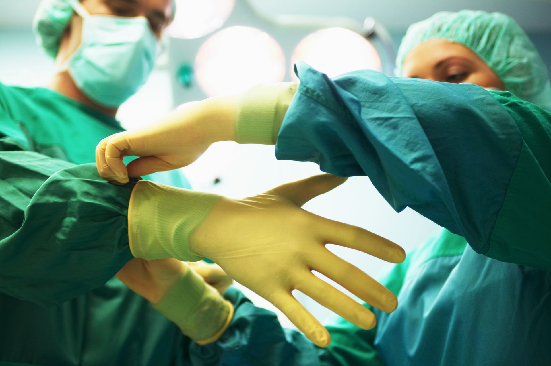A group of surgeons putting on gloves in an operating room
