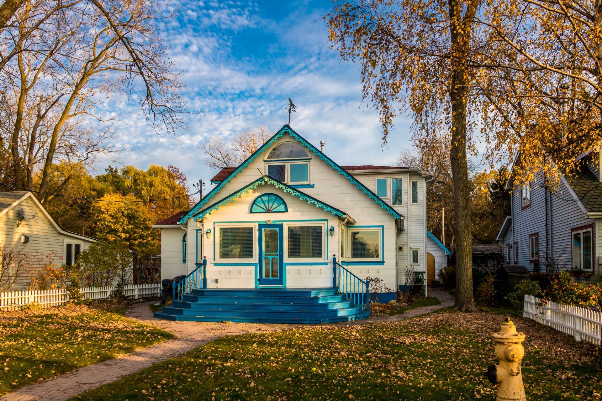 A white and blue house with a fire hydrant in front of it.