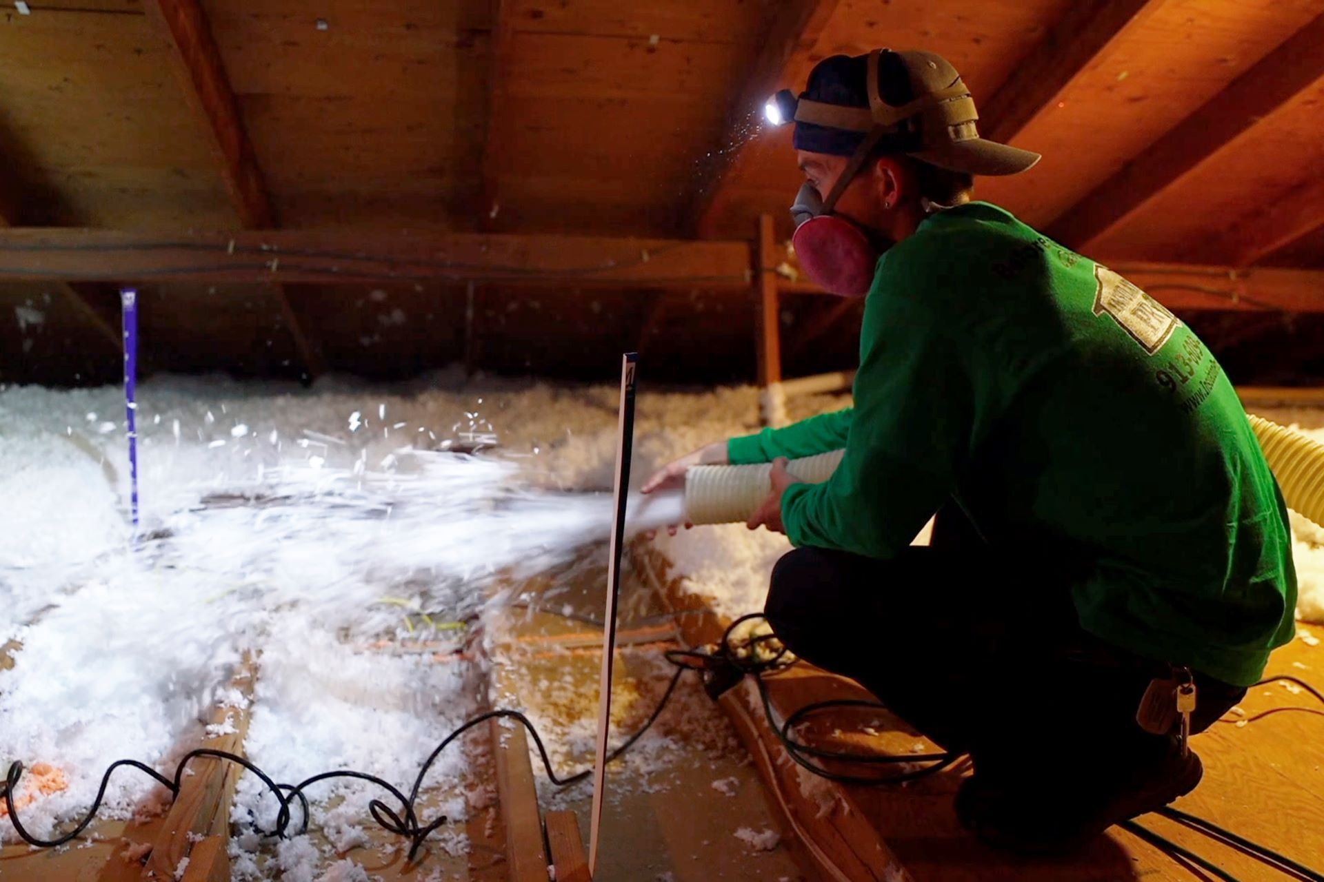 A man wearing a mask is working in an attic.