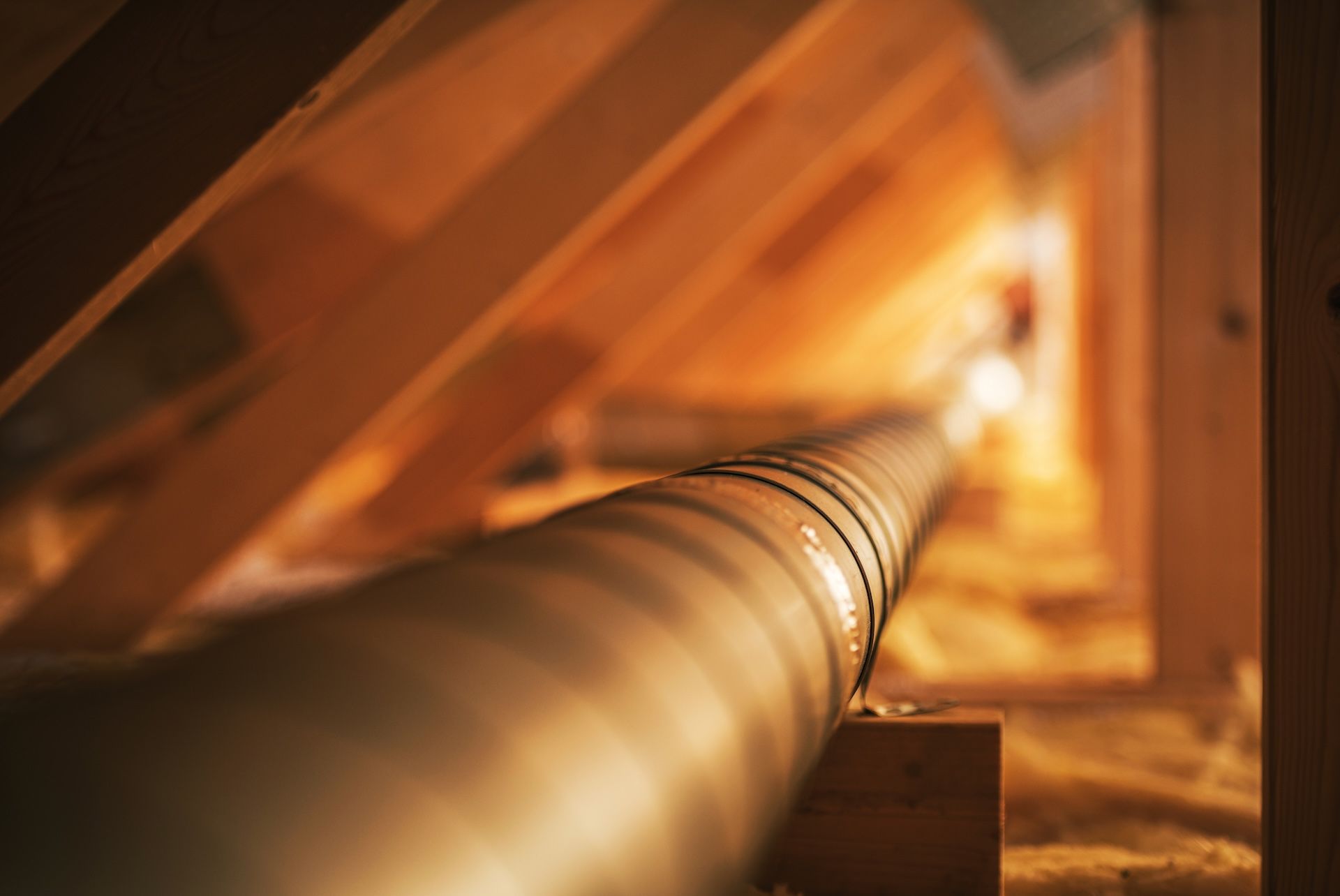 Long metal pipe running through a warm-lit industrial tunnel