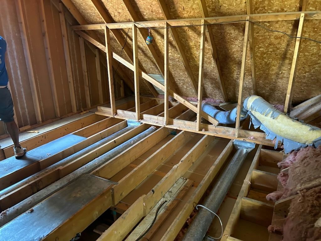 A man is standing in the attic of a house under construction.