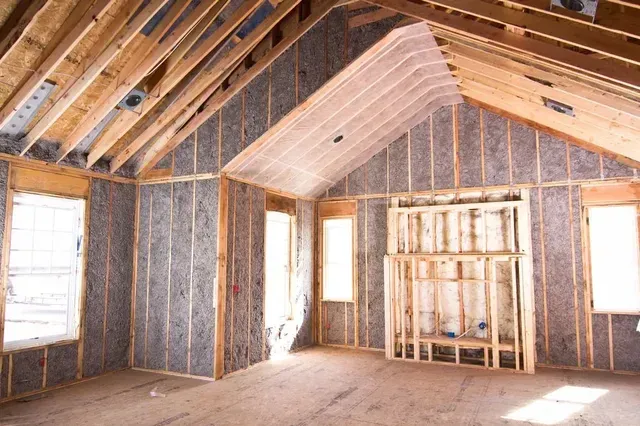 An empty room in a house under construction with a vaulted ceiling.