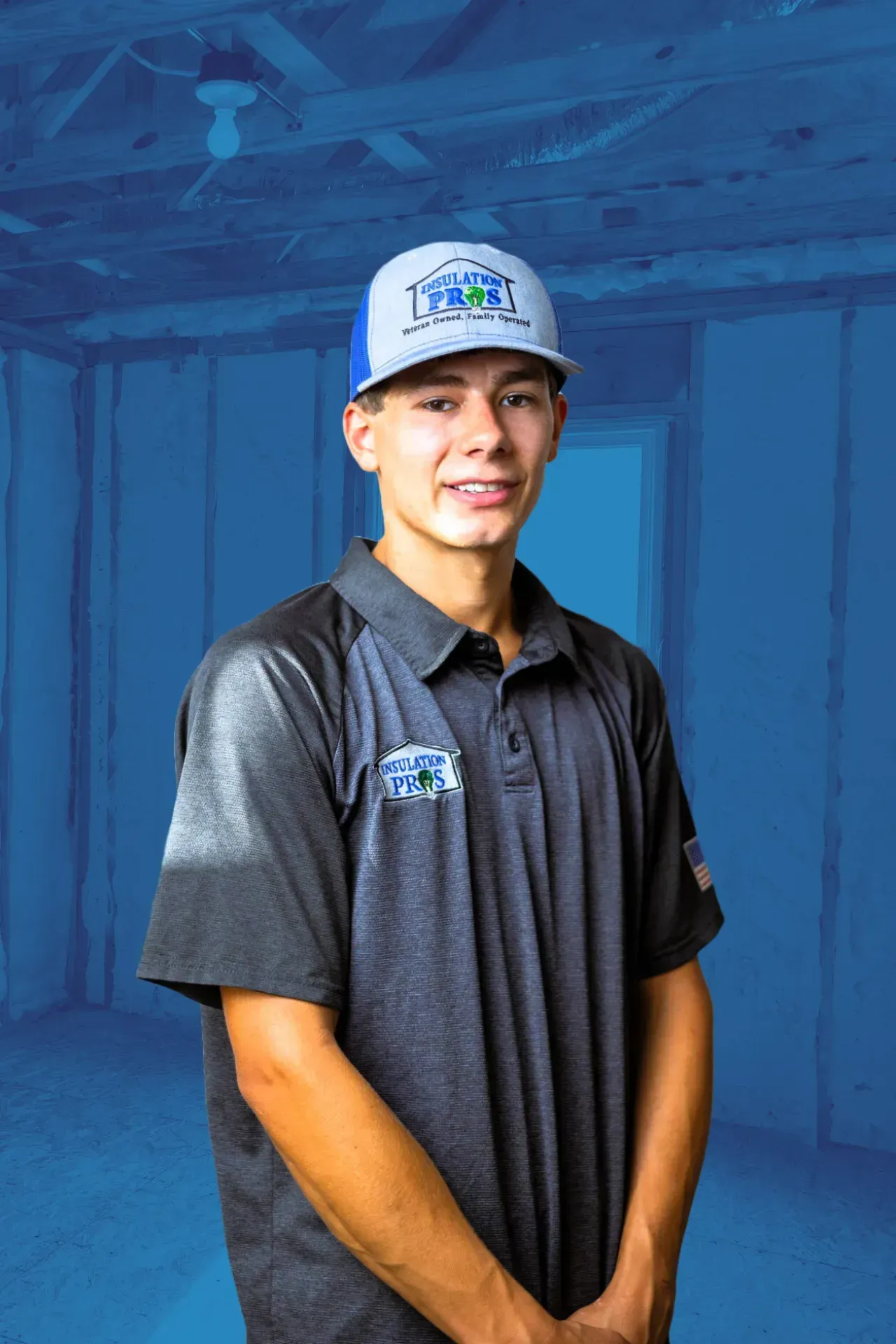 A young man wearing a hat and a polo shirt is standing in an empty room.