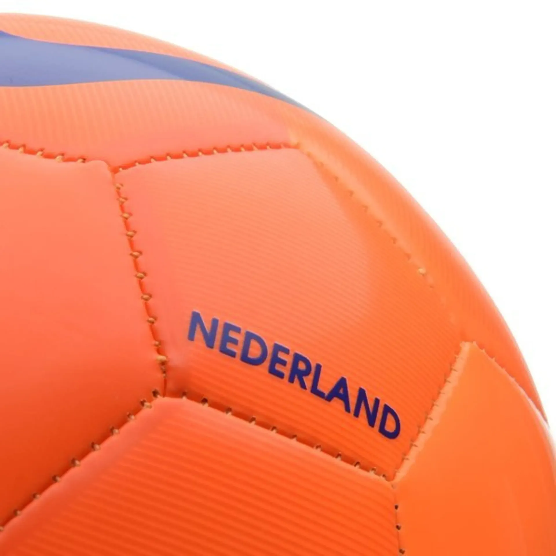 Soccer player kicking ball, goalkeeper dives, both in bright uniforms on green field.