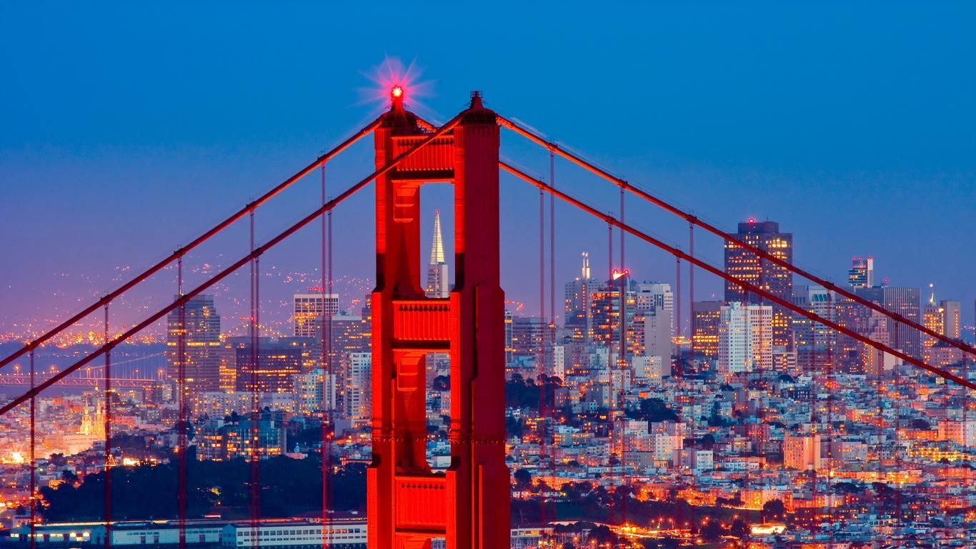 Golden Gate Bridge in San Francisco with city lights and blue twilight sky.