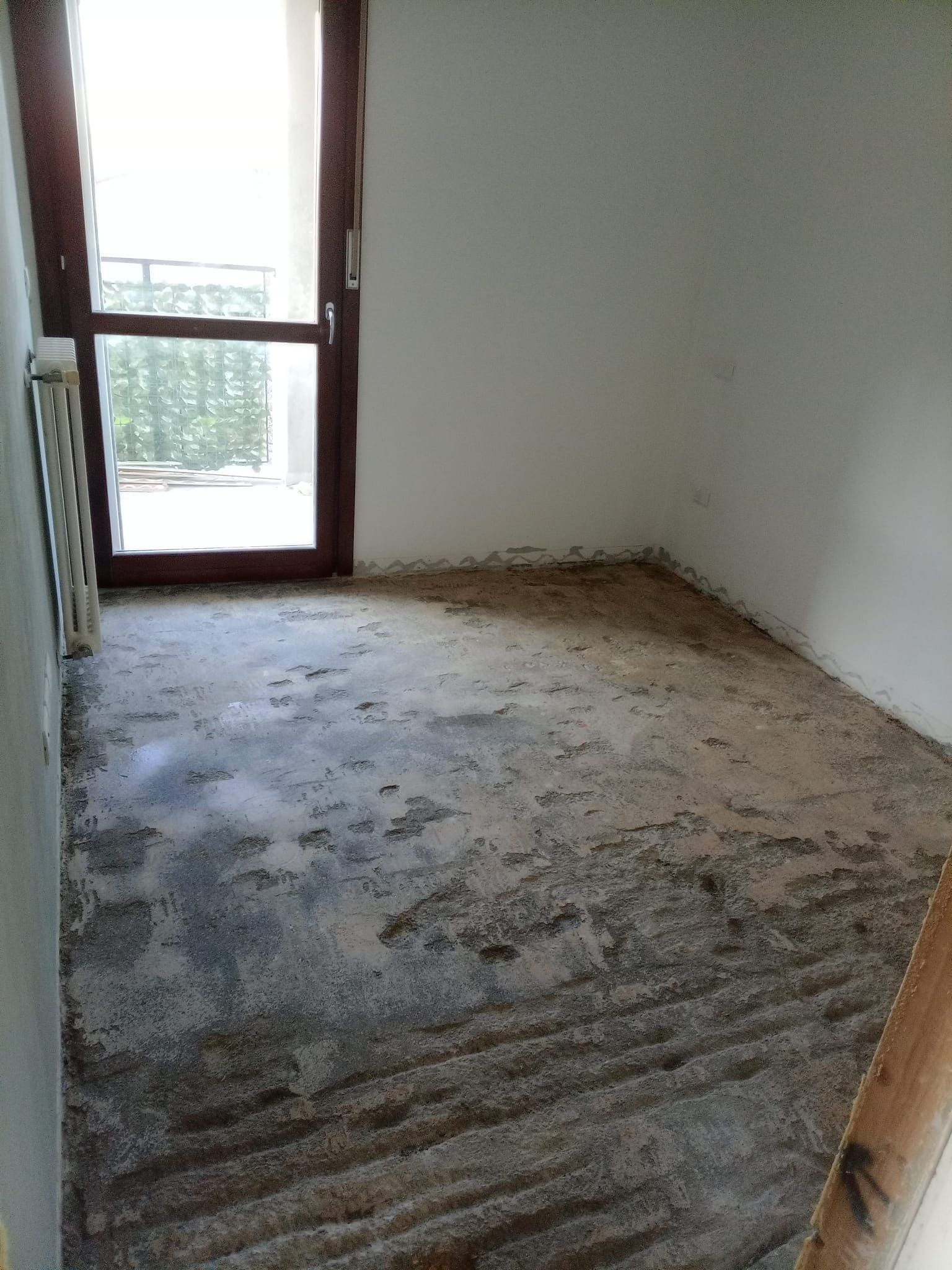 Una stanza con il pavimento sporco e una porta scorrevole in vetro.