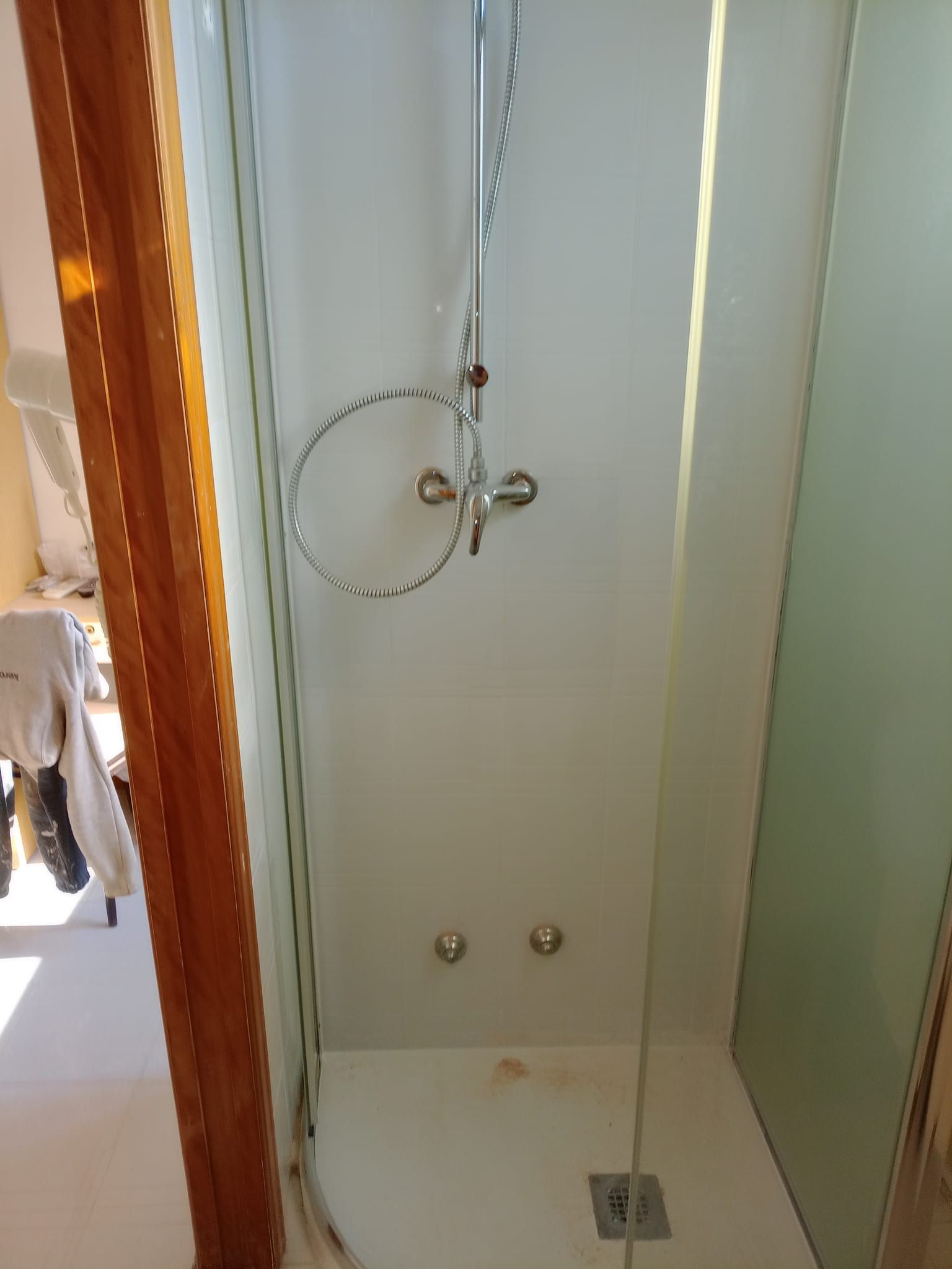 Una cabina doccia con una porta in vetro e un soffione