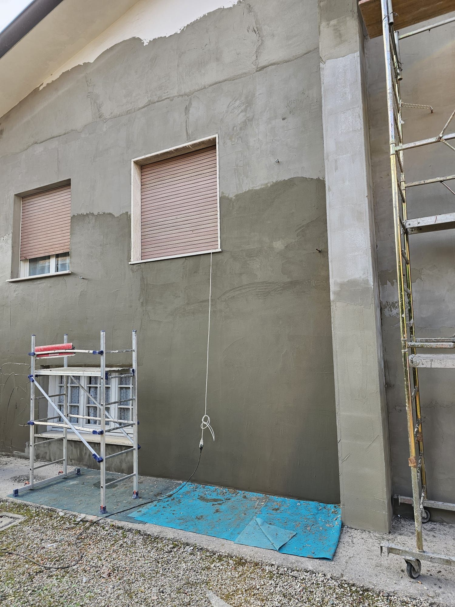 Si sta dipingendo una casa con un'impalcatura davanti.