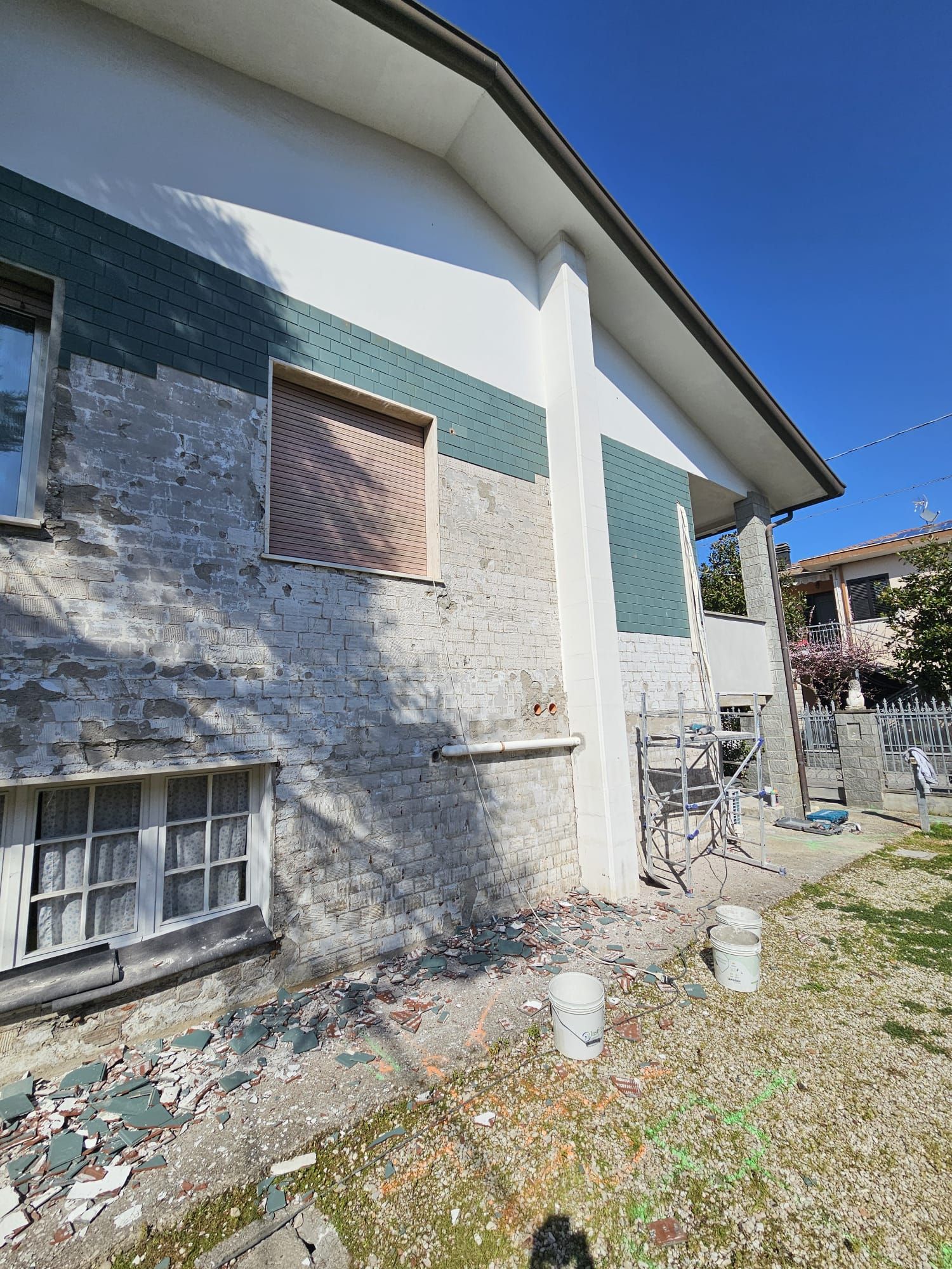 Si sta dipingendo una casa bianca con una striscia verde sul lato.