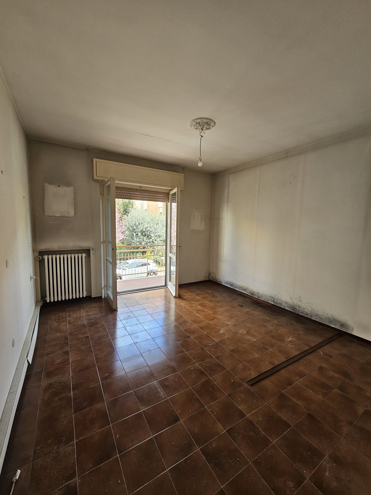 Una stanza vuota con pavimento piastrellato e una porta scorrevole in vetro.