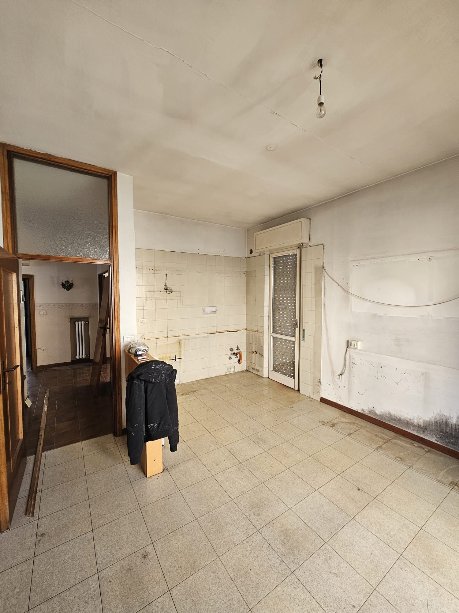 Una stanza vuota con pavimento piastrellato e una porta.