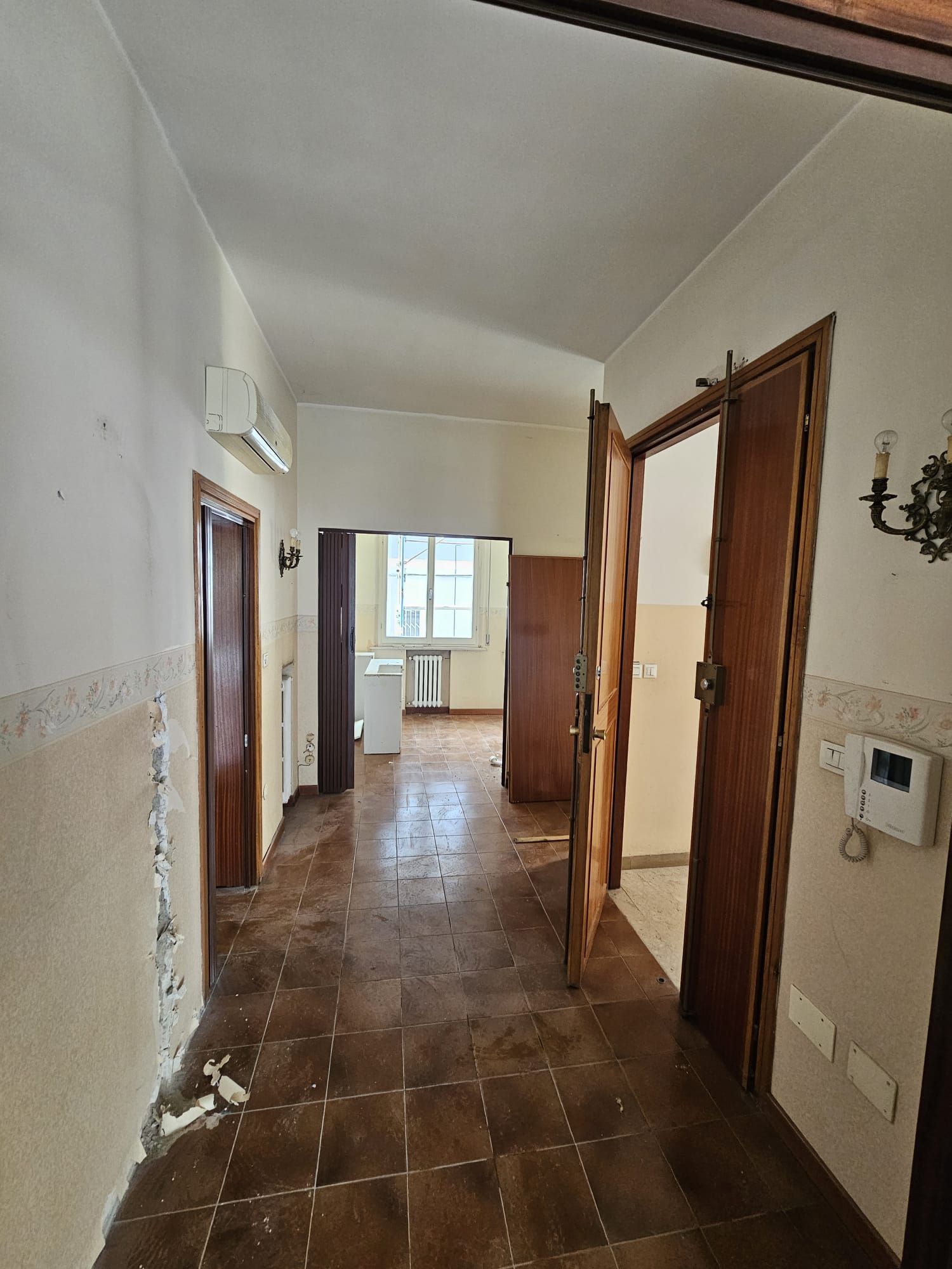 Un corridoio con pavimento piastrellato e porte in legno