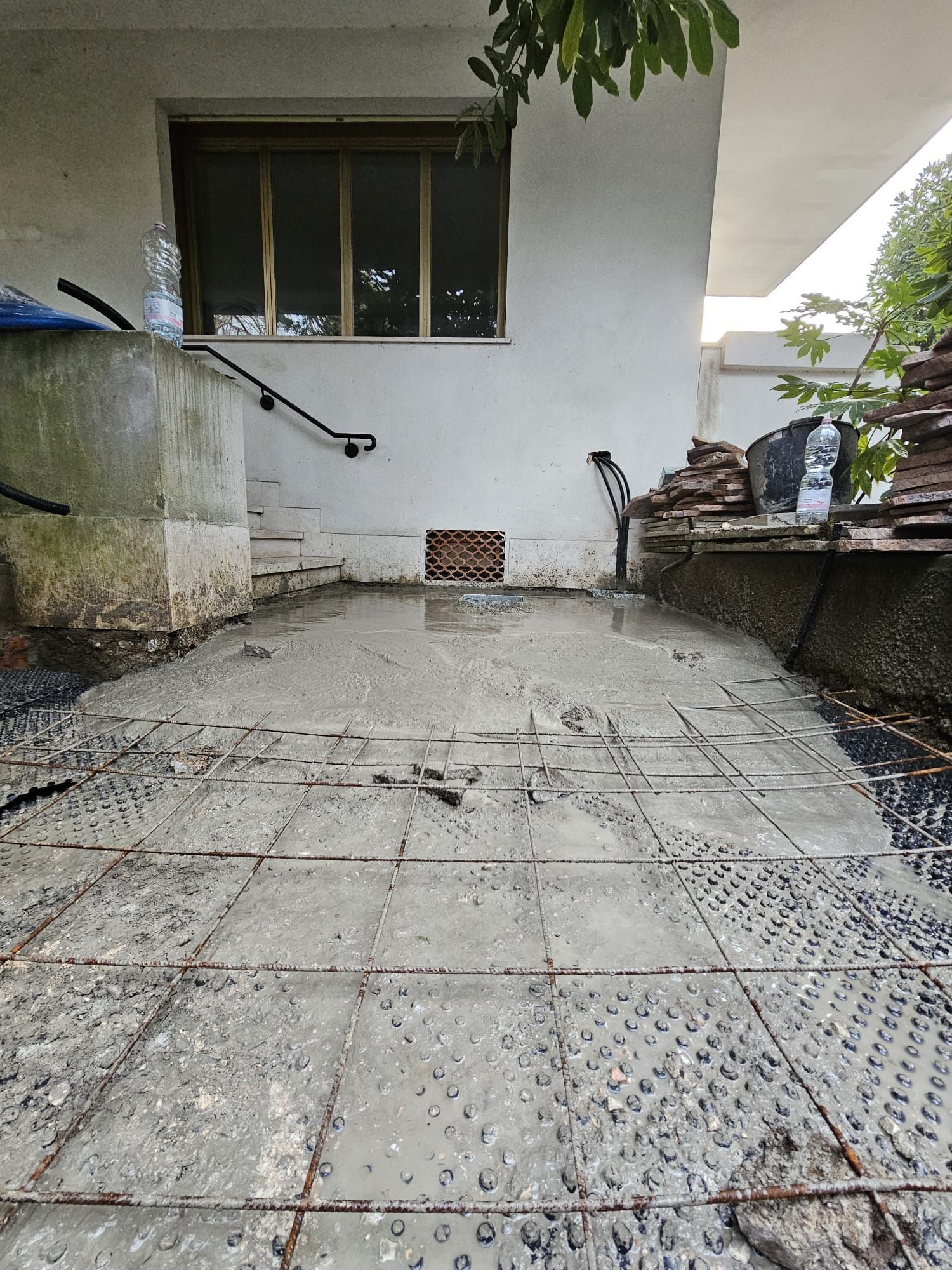 Un pavimento piastrellato sporco di fronte a un edificio bianco con una finestra.