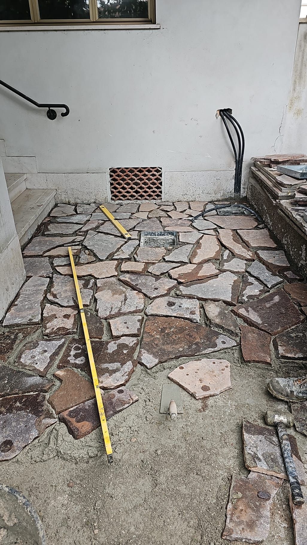 Un metro a nastro giallo è appoggiato su un pavimento di pietra.