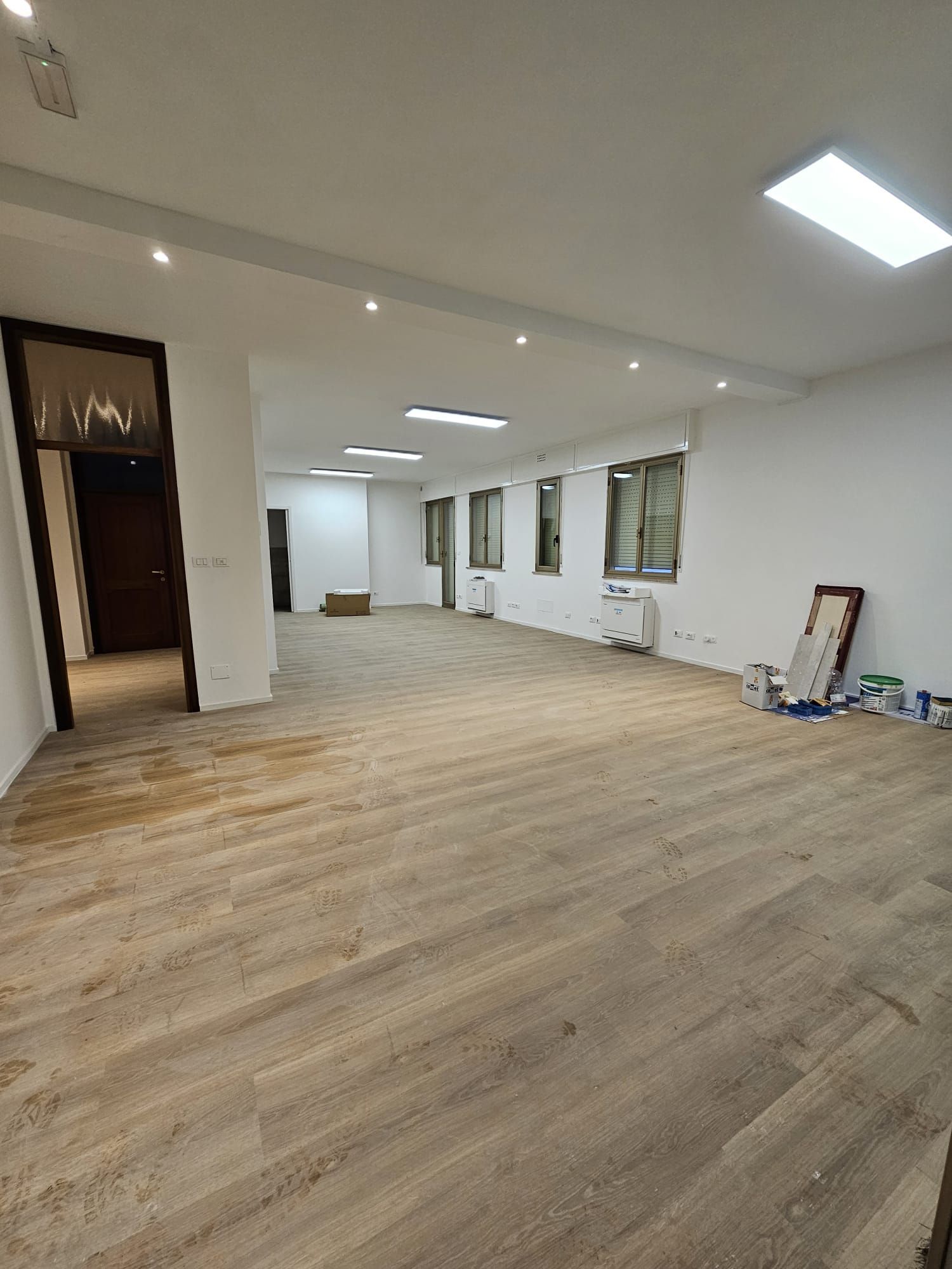 Una grande stanza vuota con pavimenti in legno e pareti bianche.