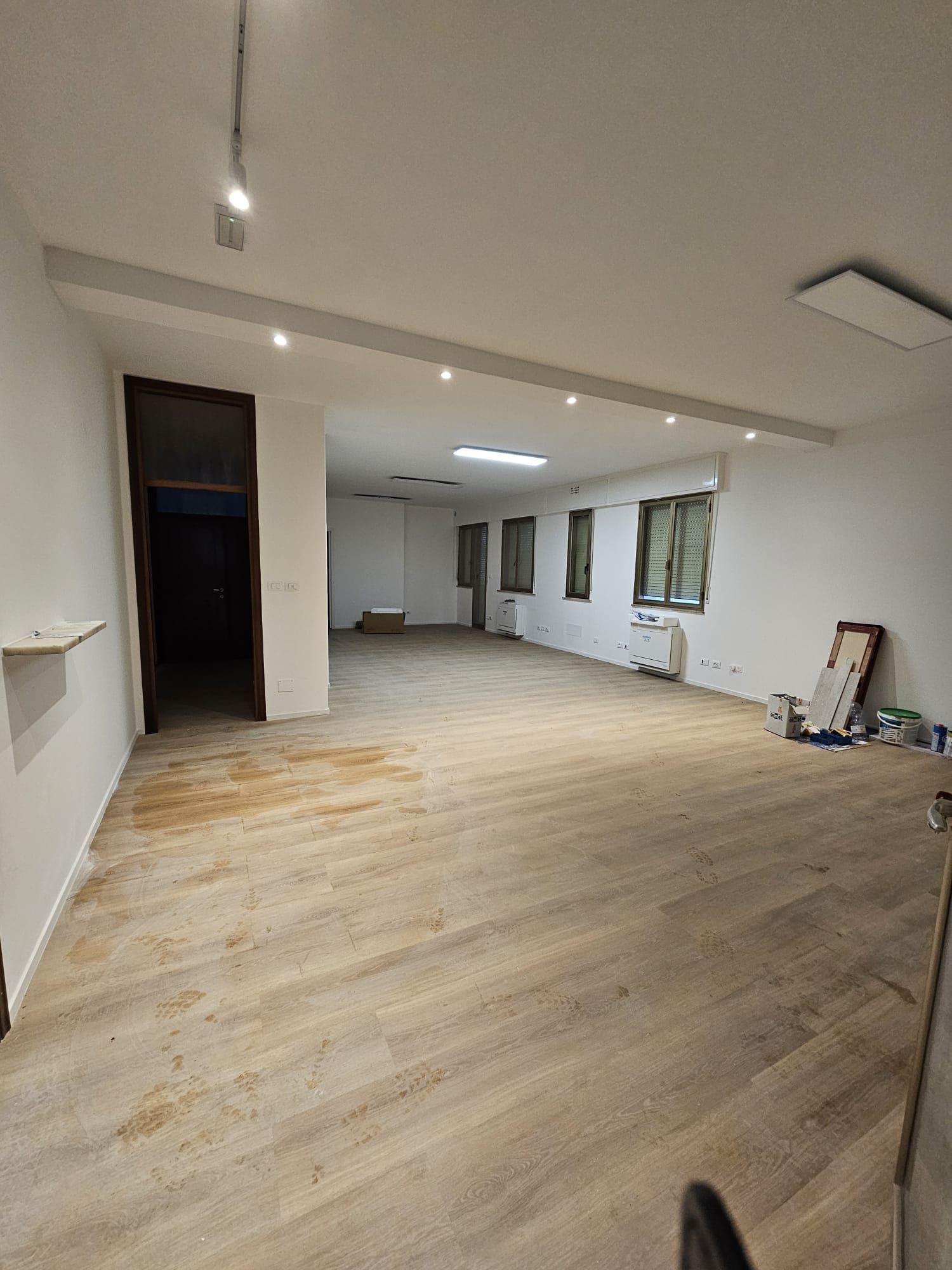 Una grande stanza vuota con pavimenti in legno e pareti bianche.