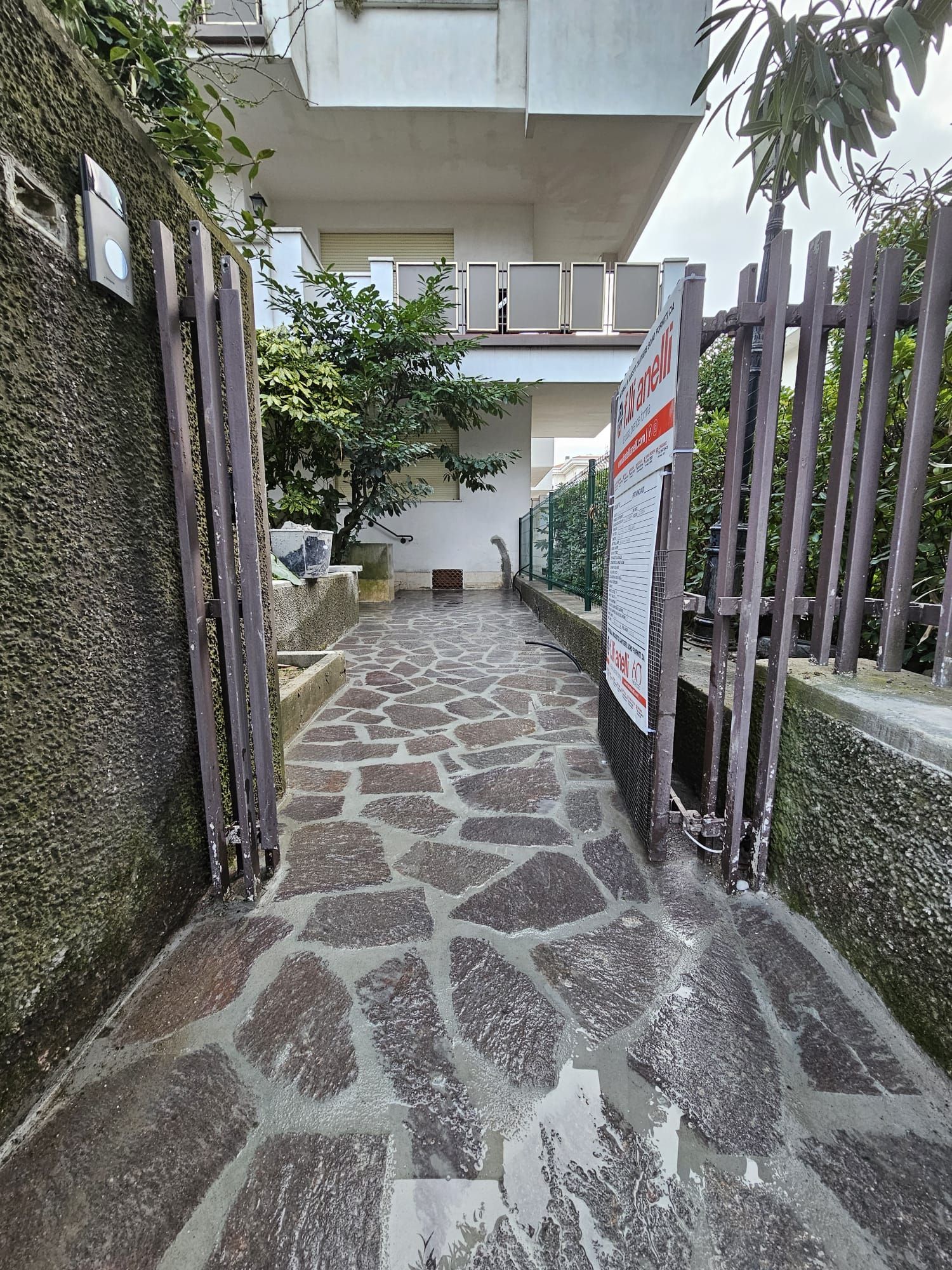 Un sentiero in pietra che conduce a un edificio con un cancello di legno.