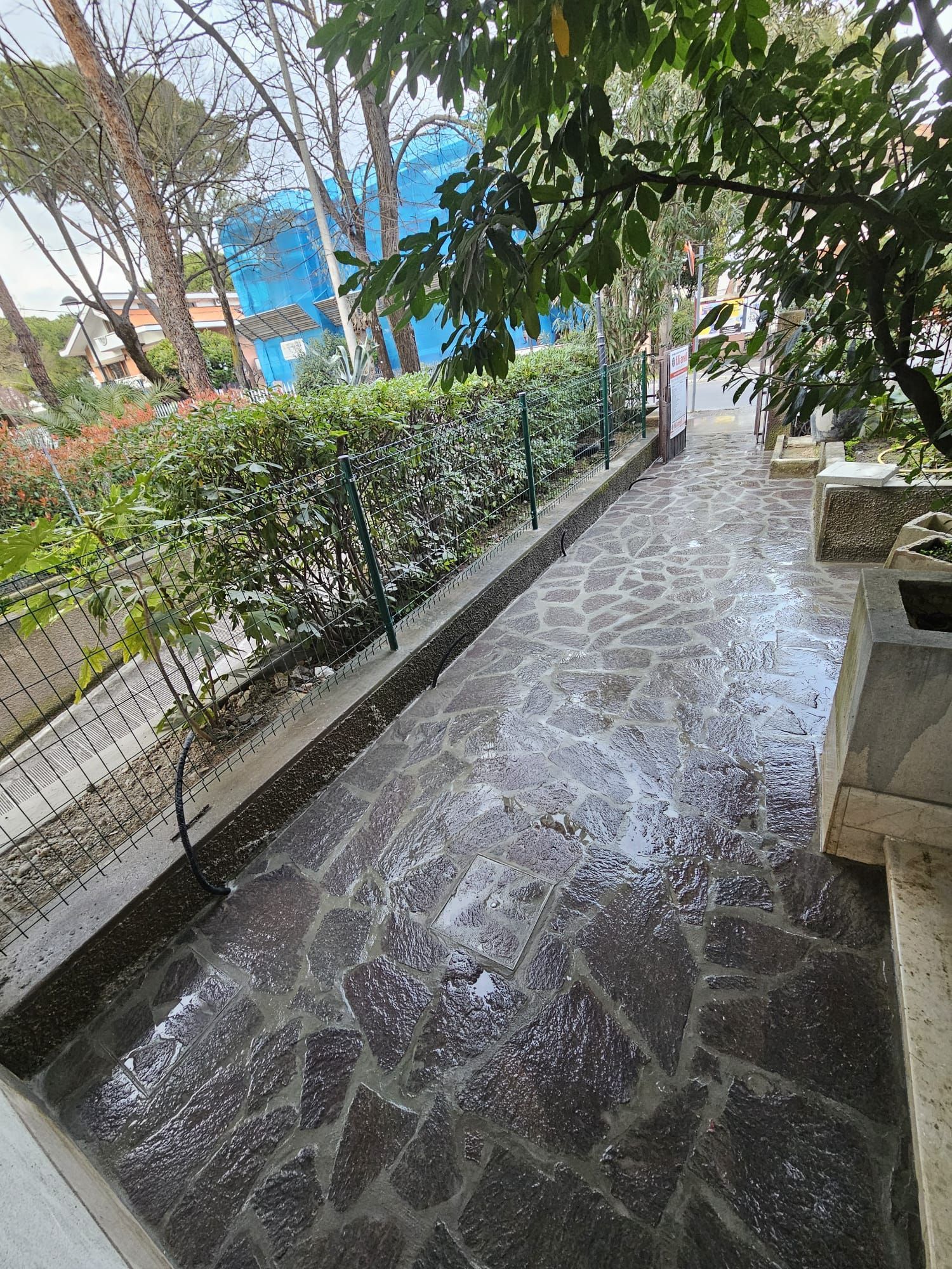 Un sentiero in pietra con una recinzione e cespugli ai lati.