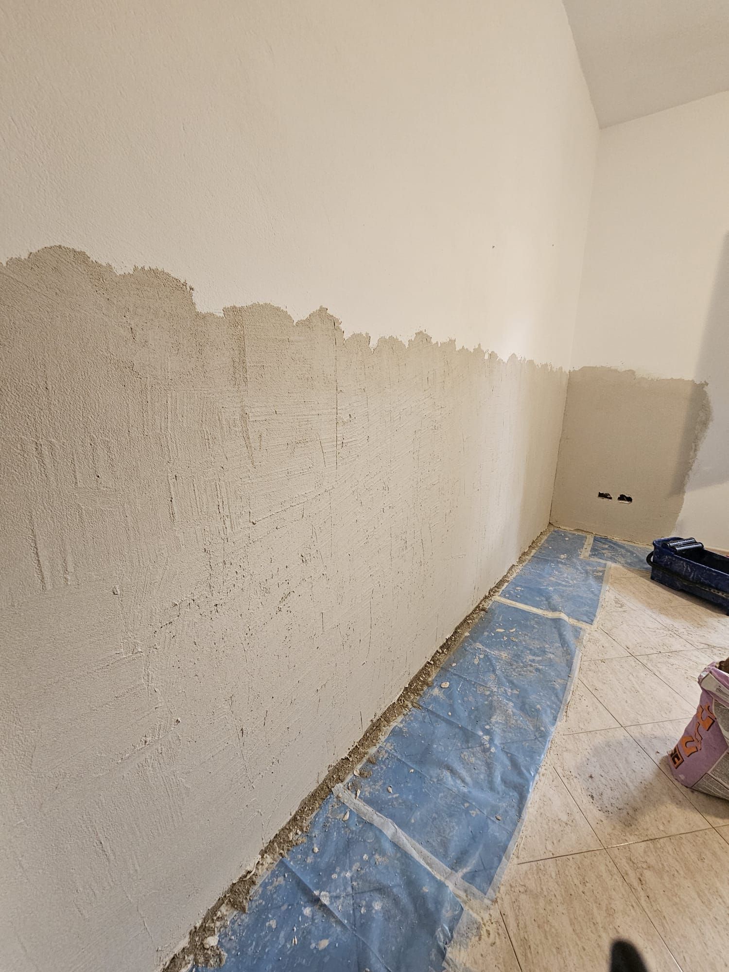 Una persona è in piedi in una stanza con un telo blu sul pavimento.