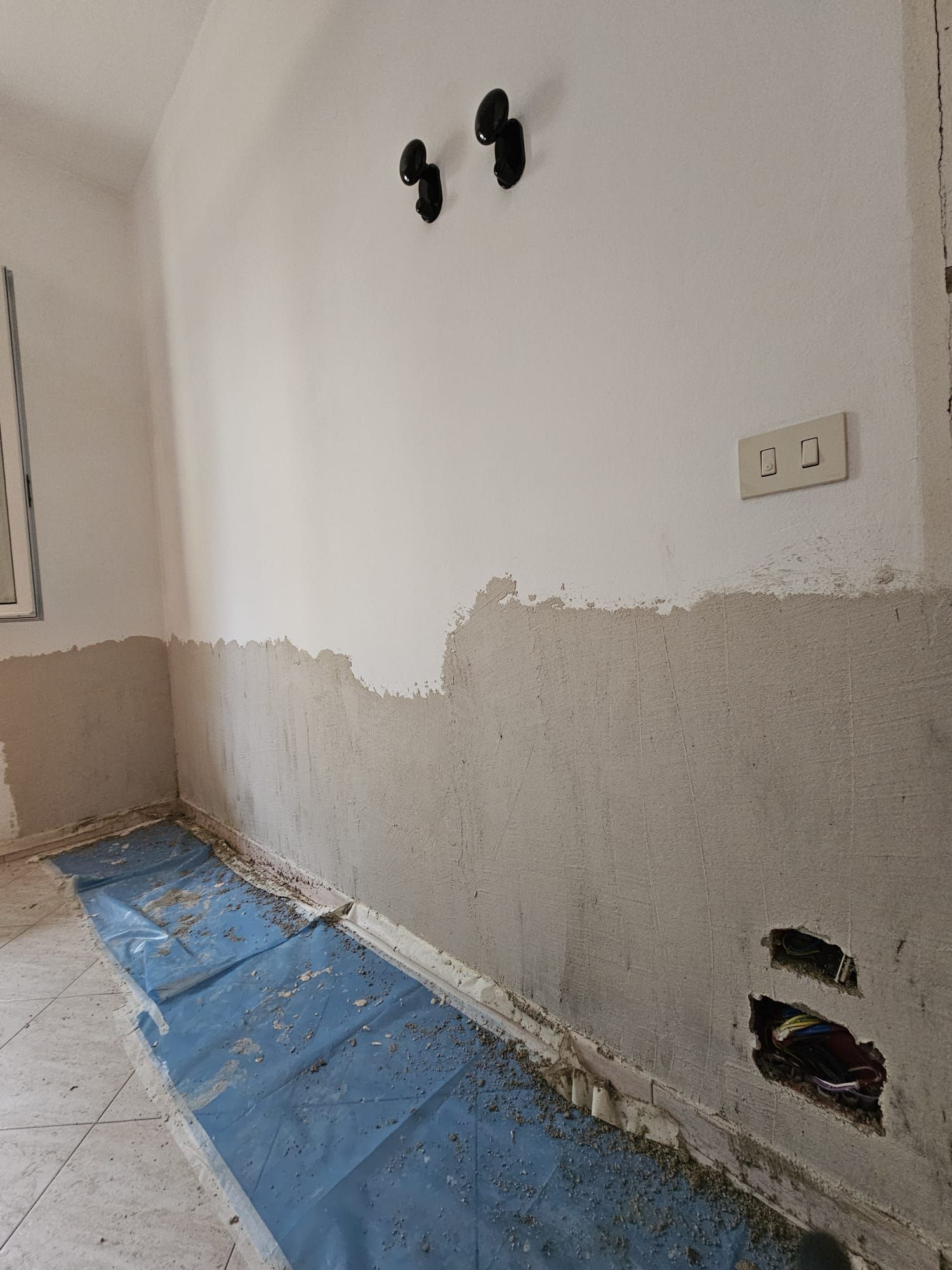 Una stanza con un telo blu sul pavimento e una parete bianca.