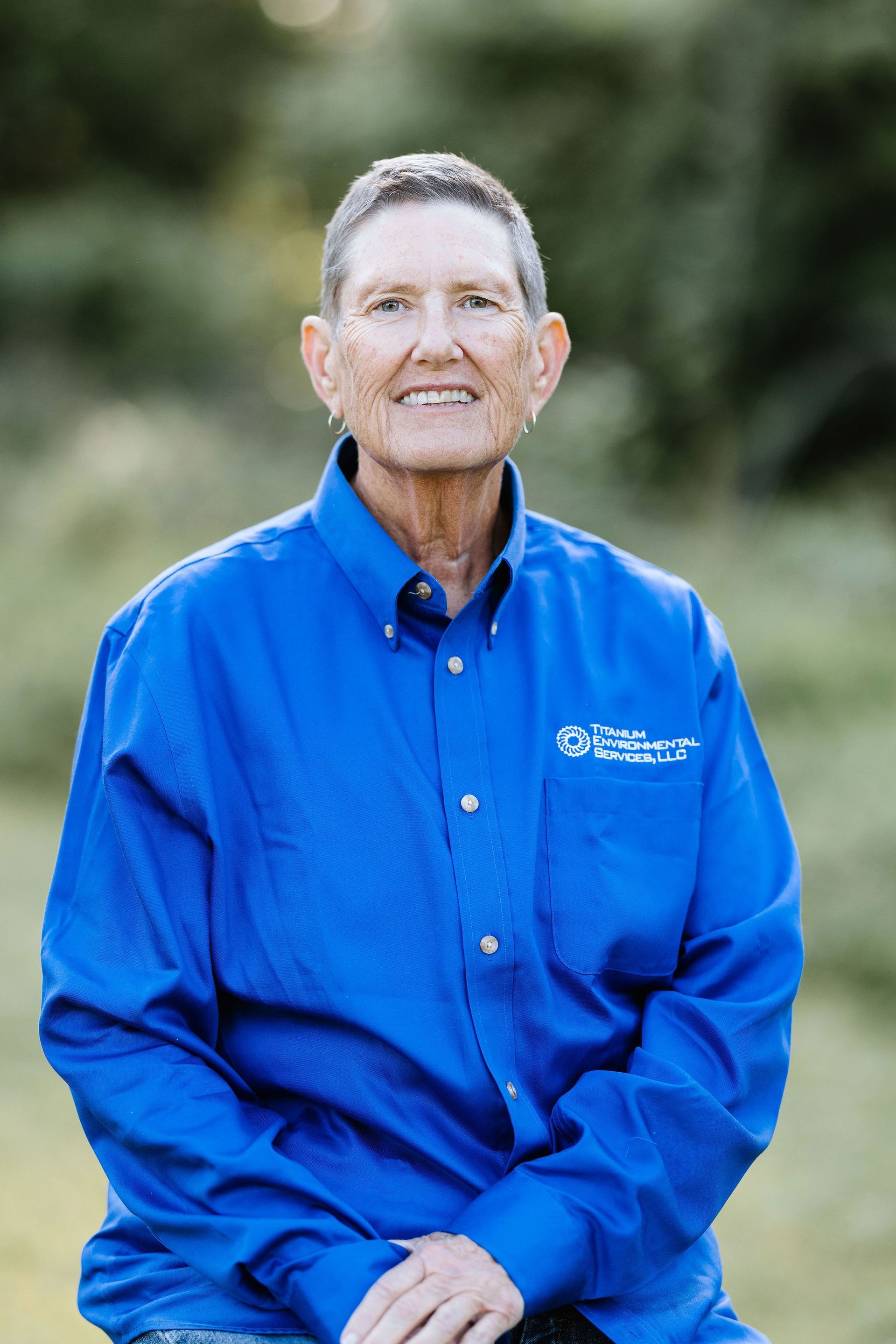 Woman wearing a blue shirt smiles outdoors.