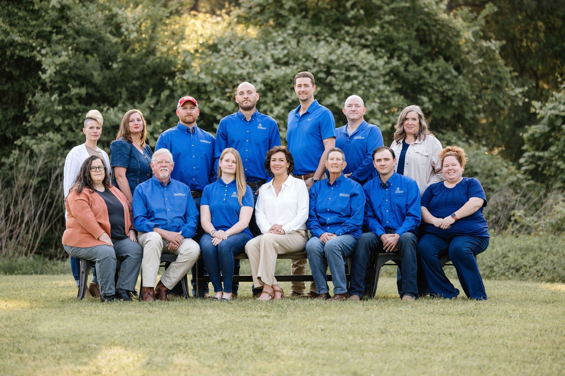 Group of people in blue shirts and business casual attire, outdoors.
