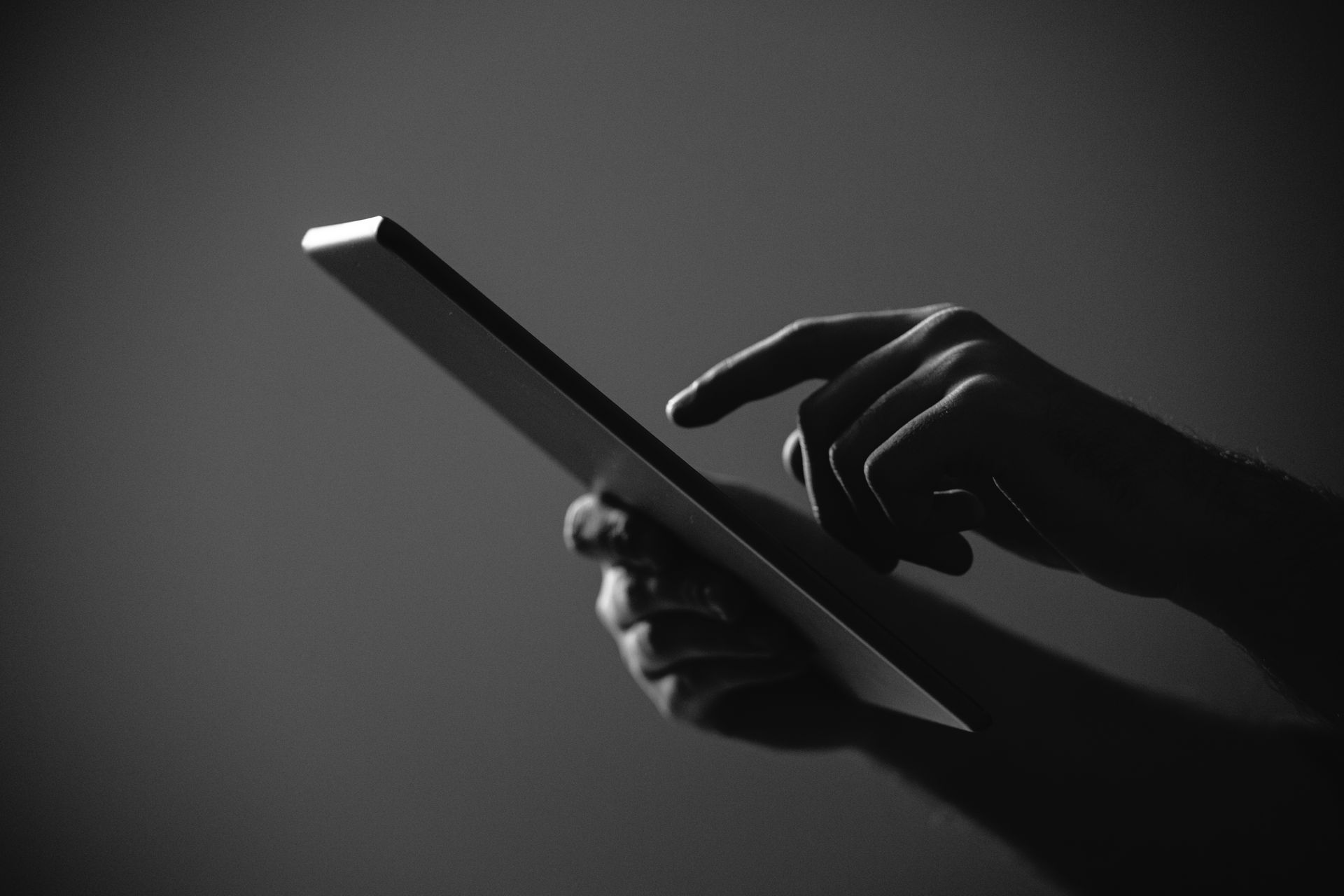 A person is holding a tablet in their hand and pointing at it.