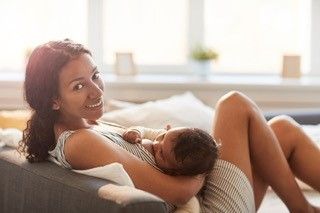 a woman is breastfeeding her baby while sitting on a couch 