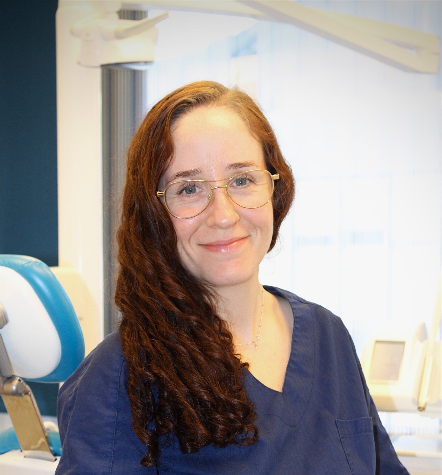 Tannlege Christian med briller og skjegg, iført blå skjorte og medisinsk maske, smiler til kameraet.