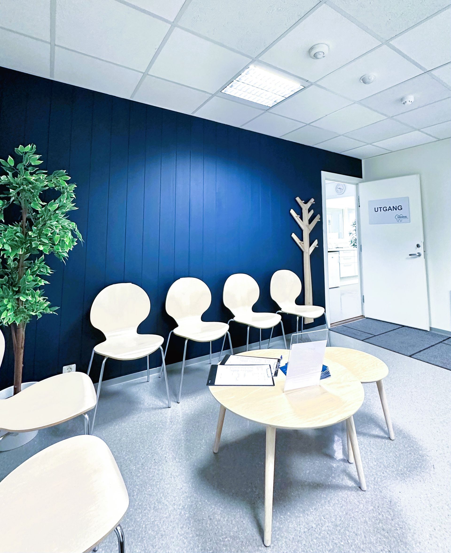 Seks kvinner i skrubber smiler i lyse omgivelser innendørs.