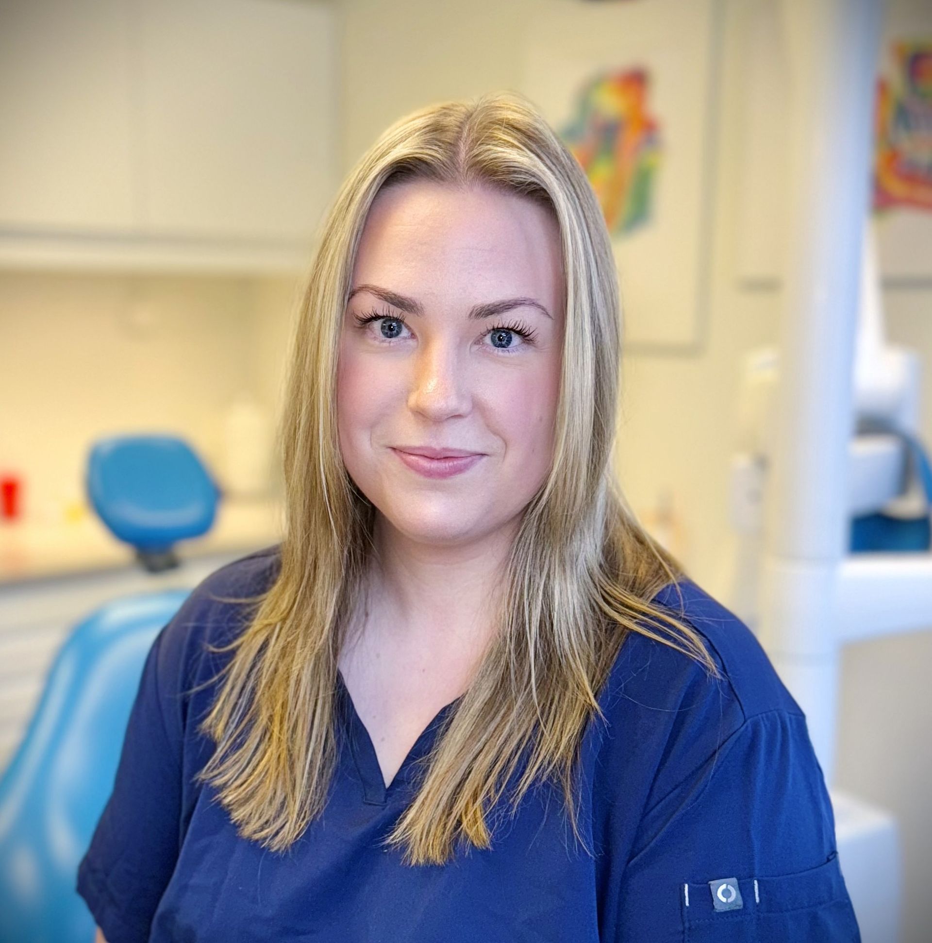 Tannlege Christian med briller og skjegg, iført blå skjorte og medisinsk maske, smiler til kameraet.