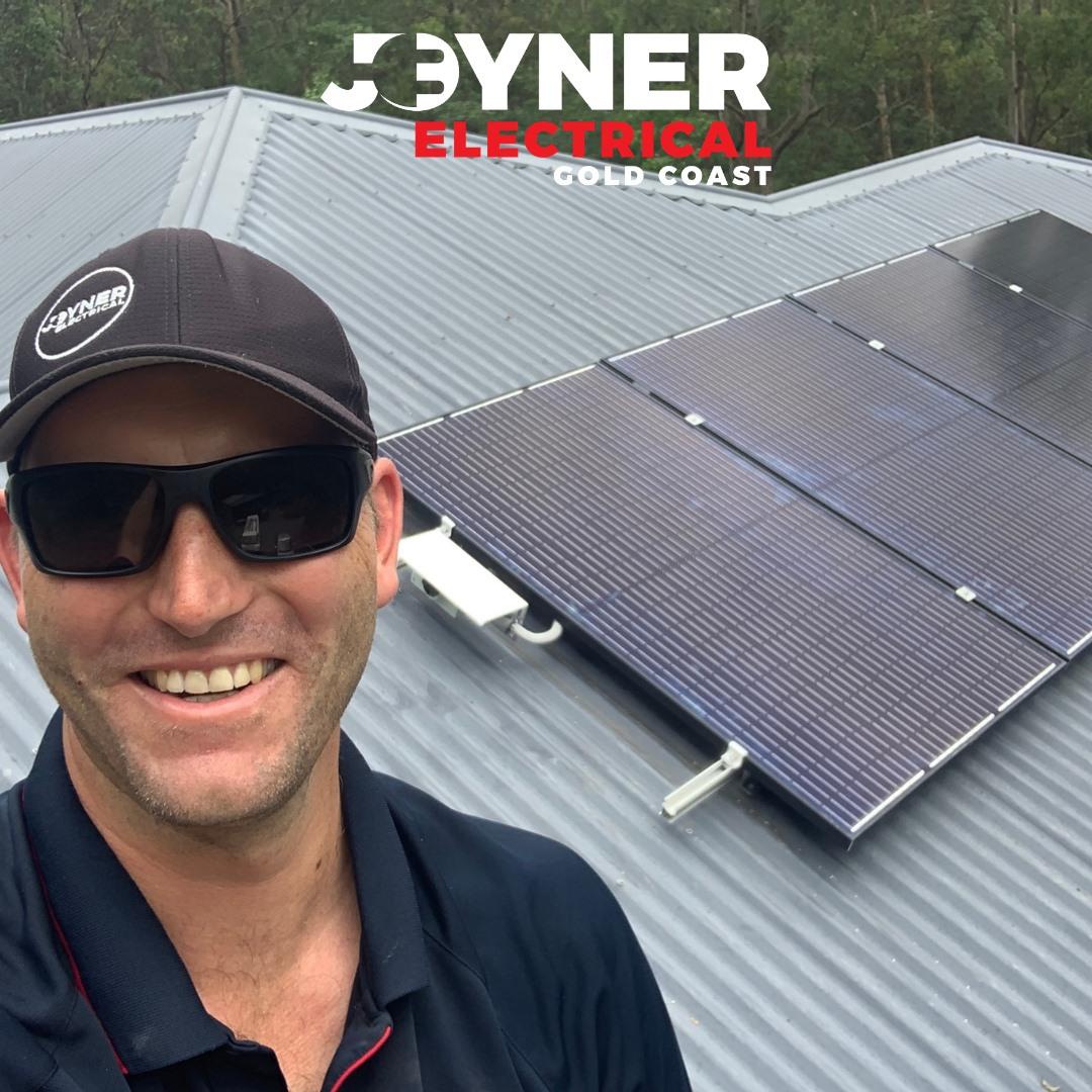 Electrician With Solar Panel in Background — Electrical Services In Carrara, QLD