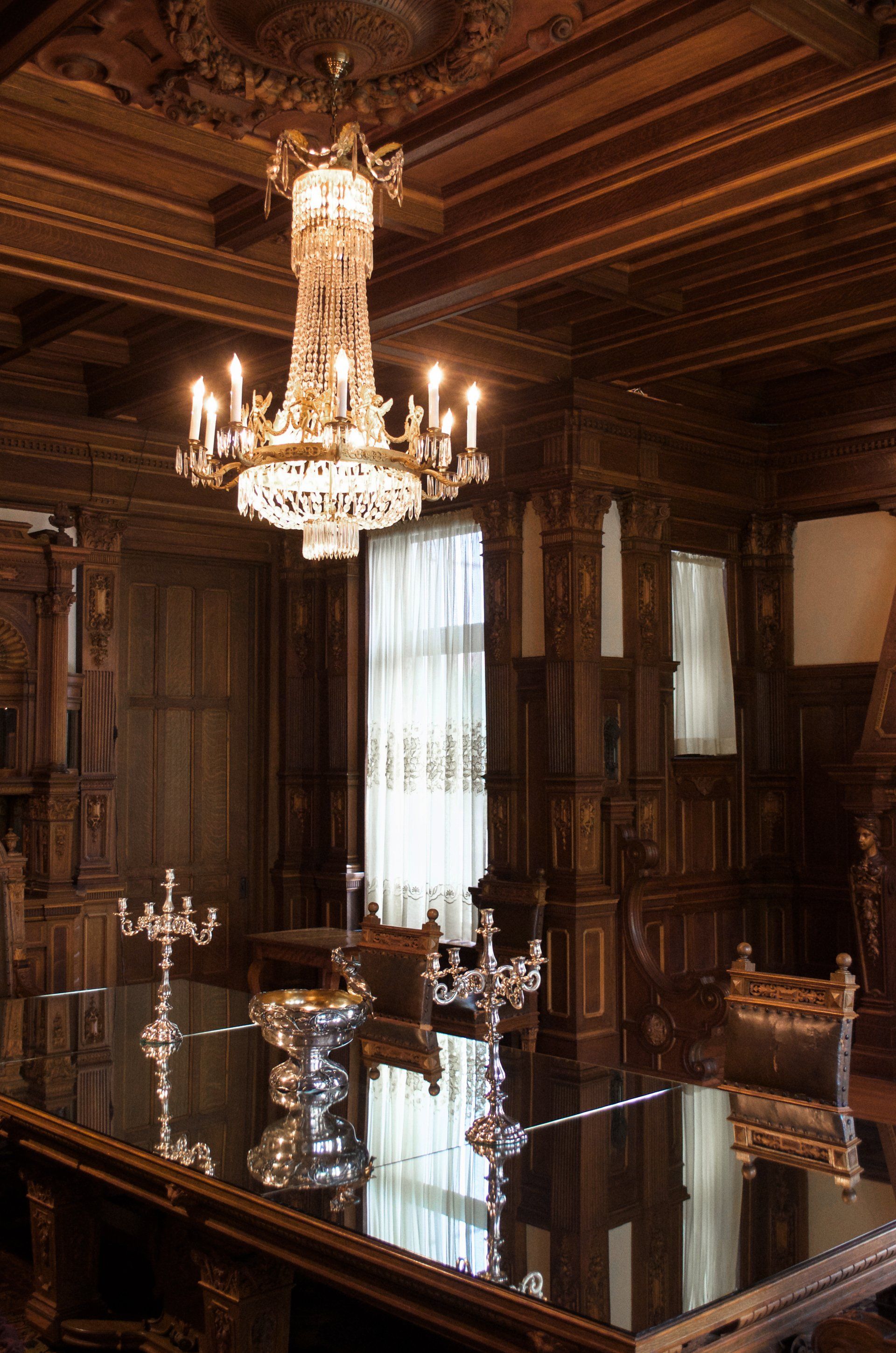 A room with a table and a chandelier hanging from the ceiling