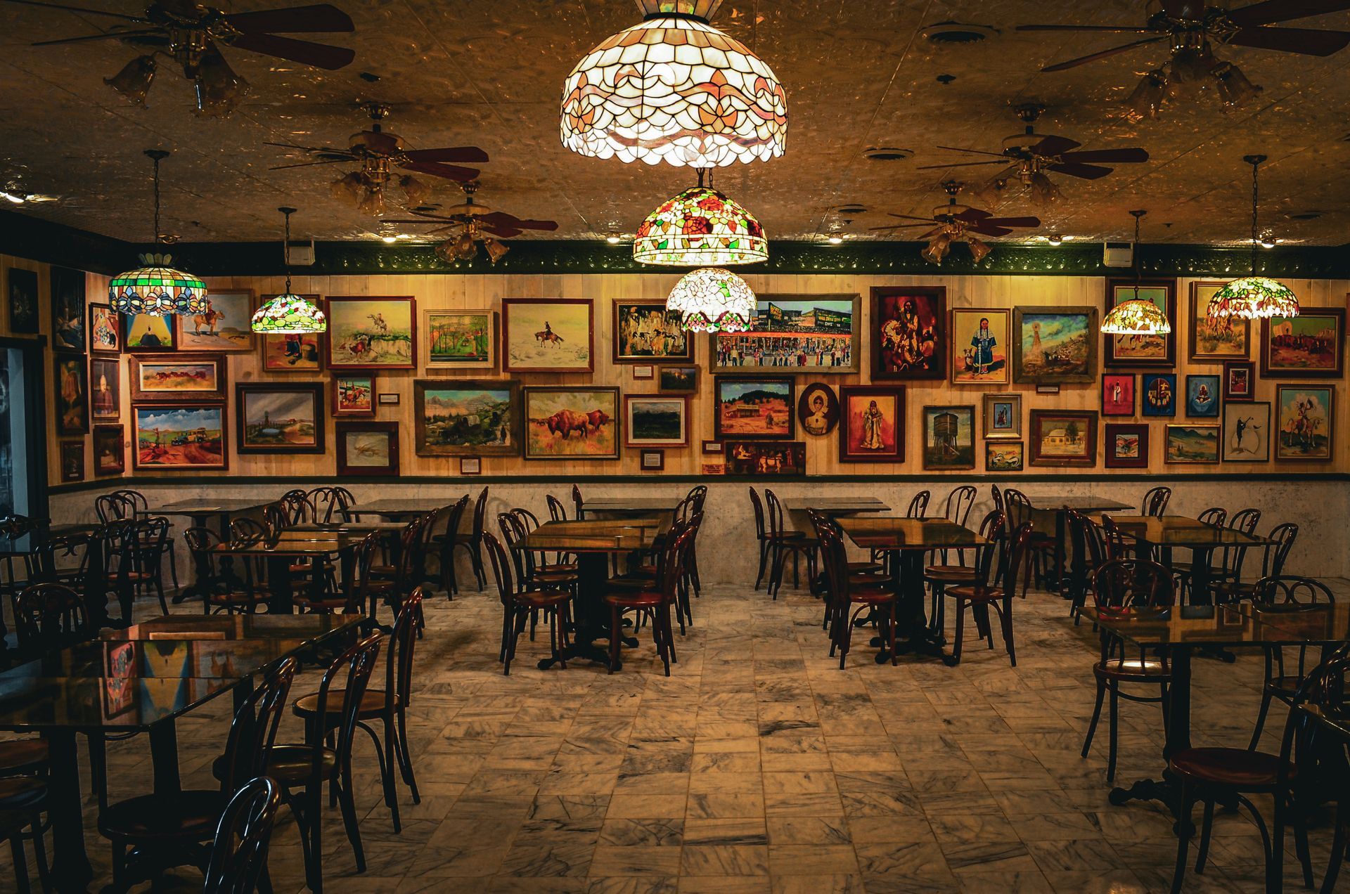 A restaurant with tables and chairs and paintings on the wall