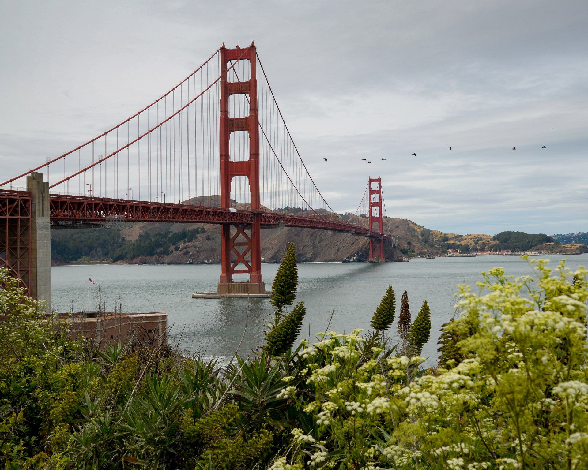 A red bridge over a body of water with trees in the foreground