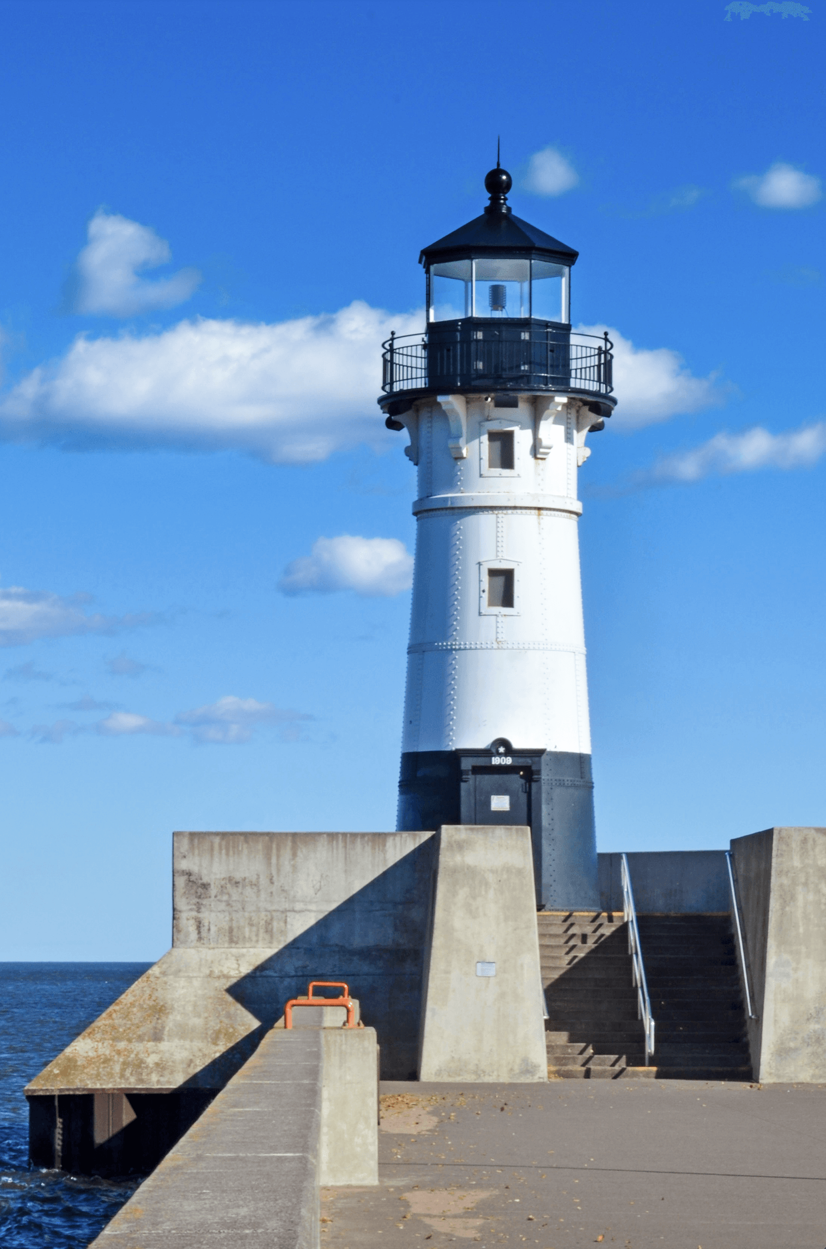 A black and white lighthouse with stairs leading up to it