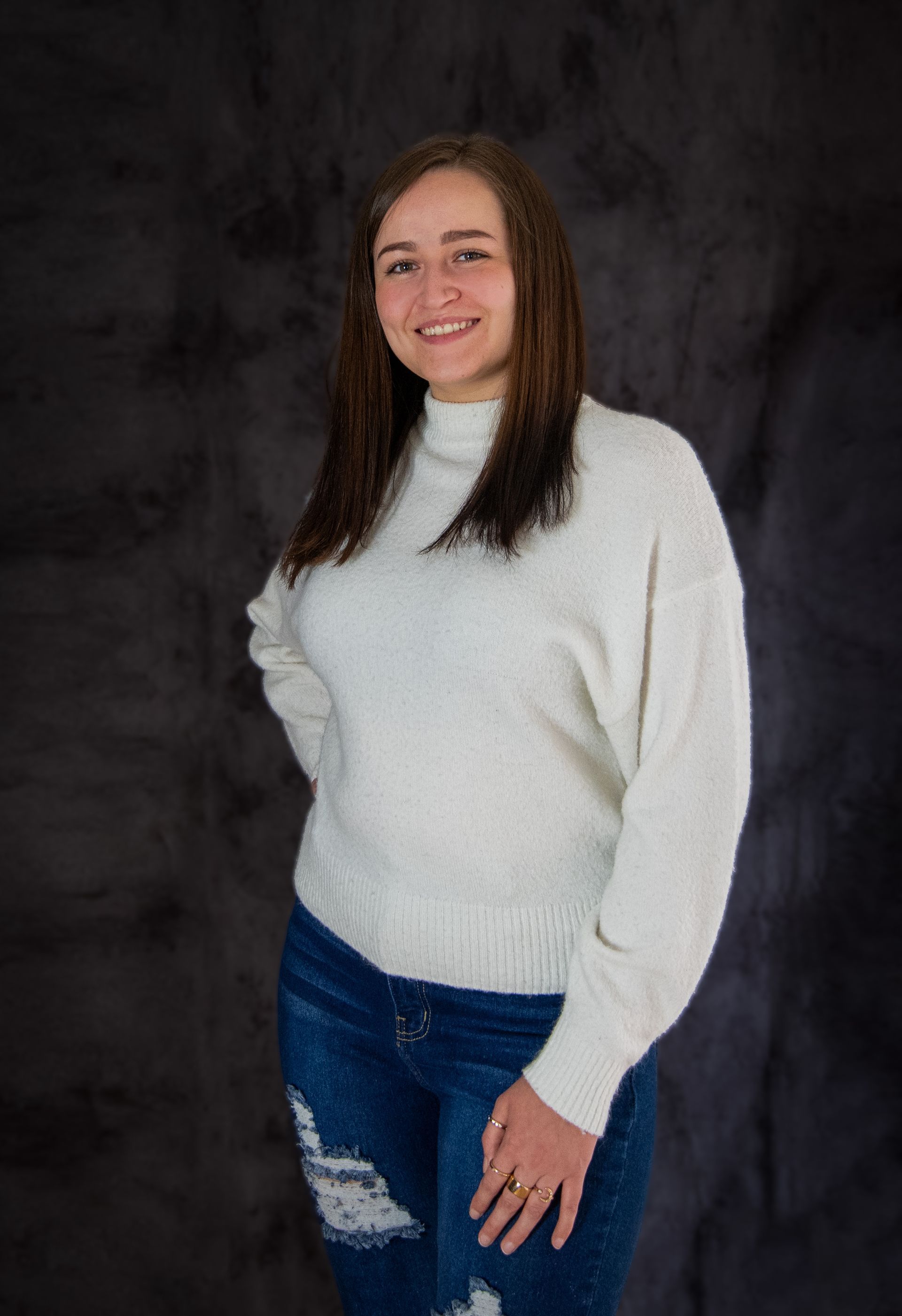 A woman is wearing a white sweater and blue jeans
