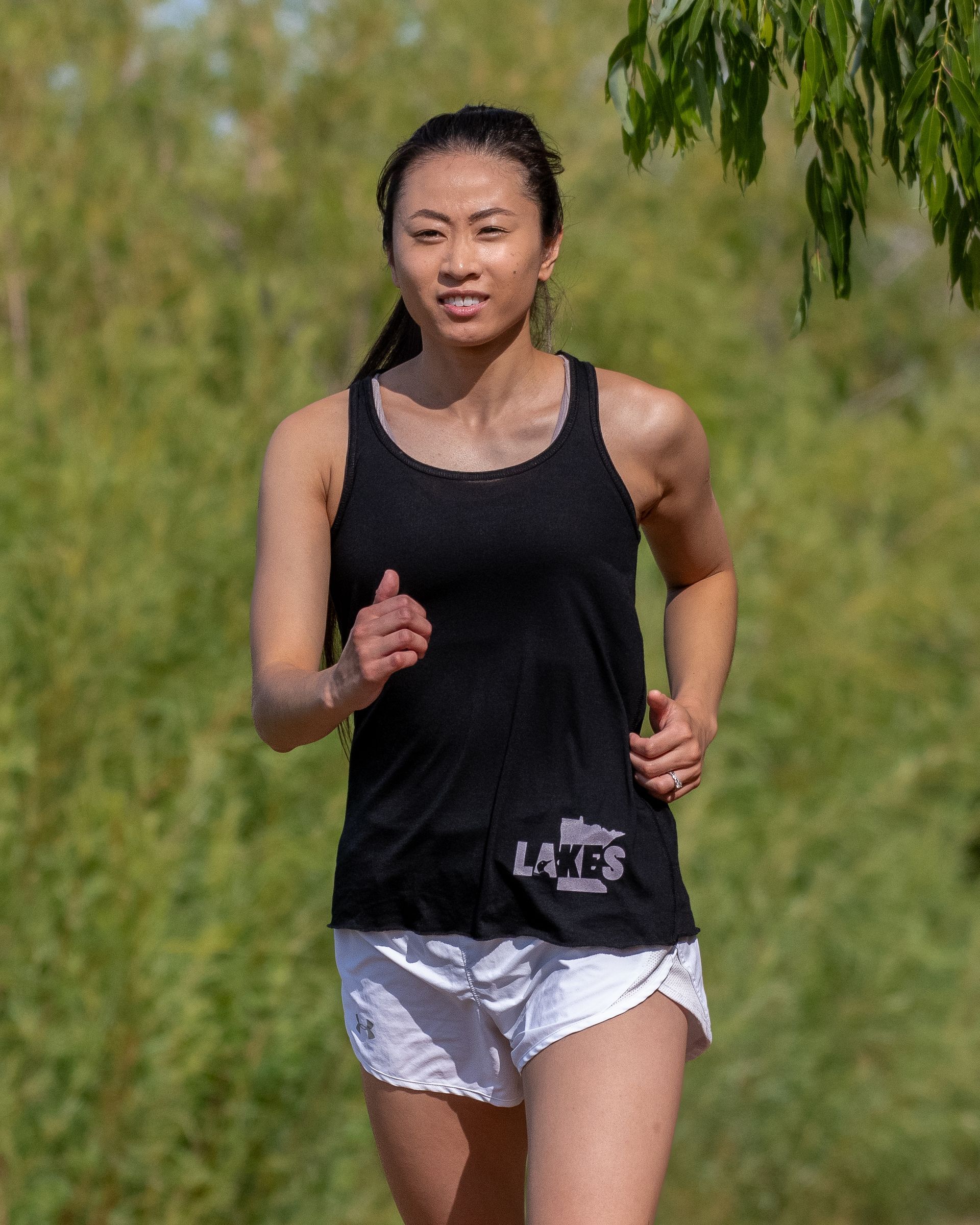 A woman in a black tank top and white shorts is running