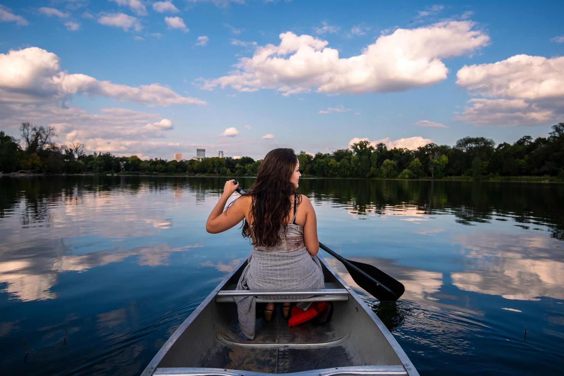 A woman is paddling a canoe on a lake