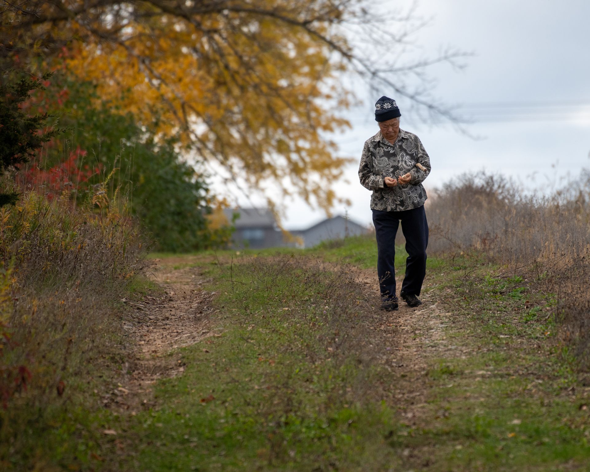 A man in a camo shirt is walking down a dirt path