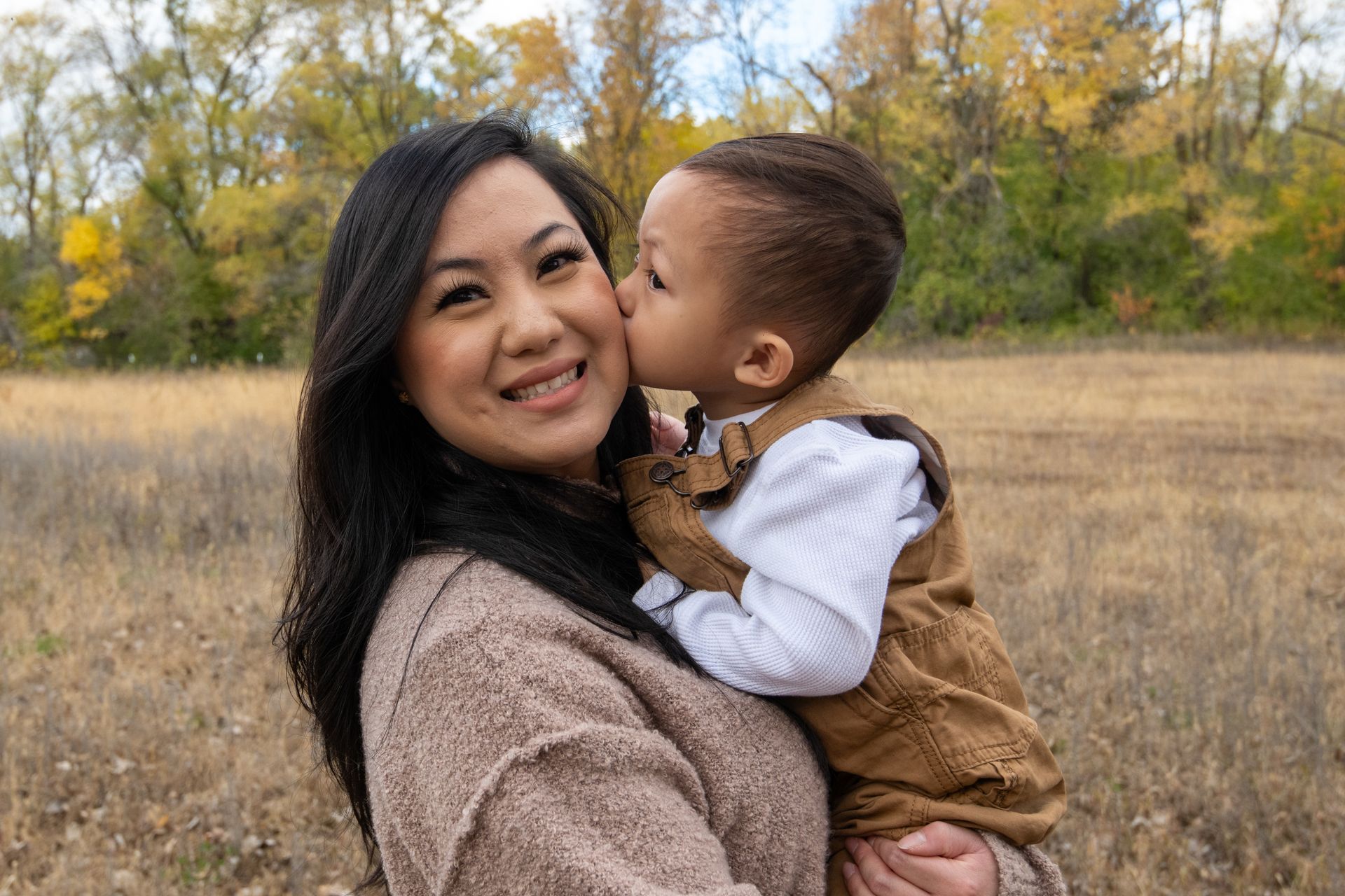 A woman is holding a baby in her arms and the baby is kissing her on the cheek.