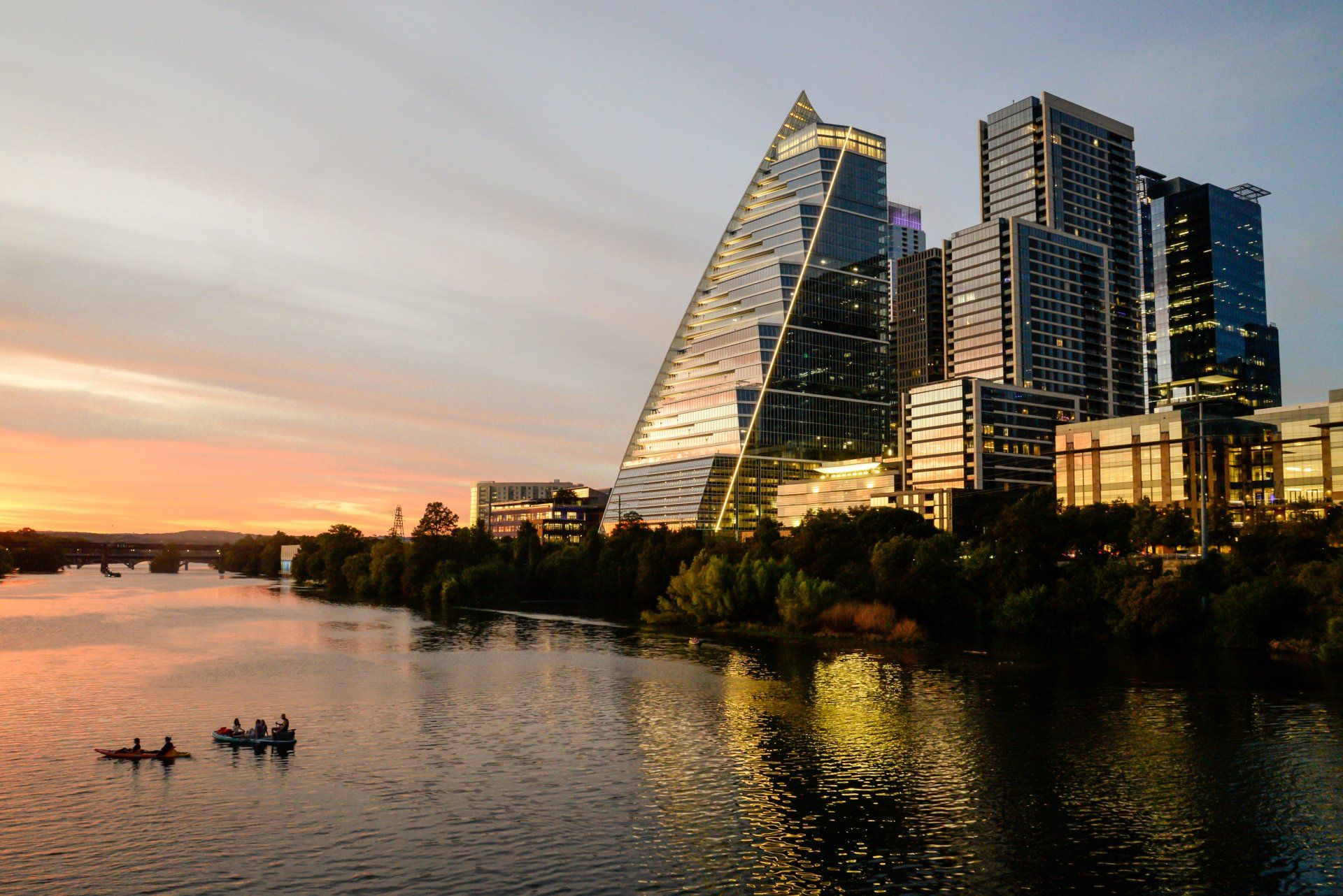 A group of people in kayaks on a river in front of a city skyline