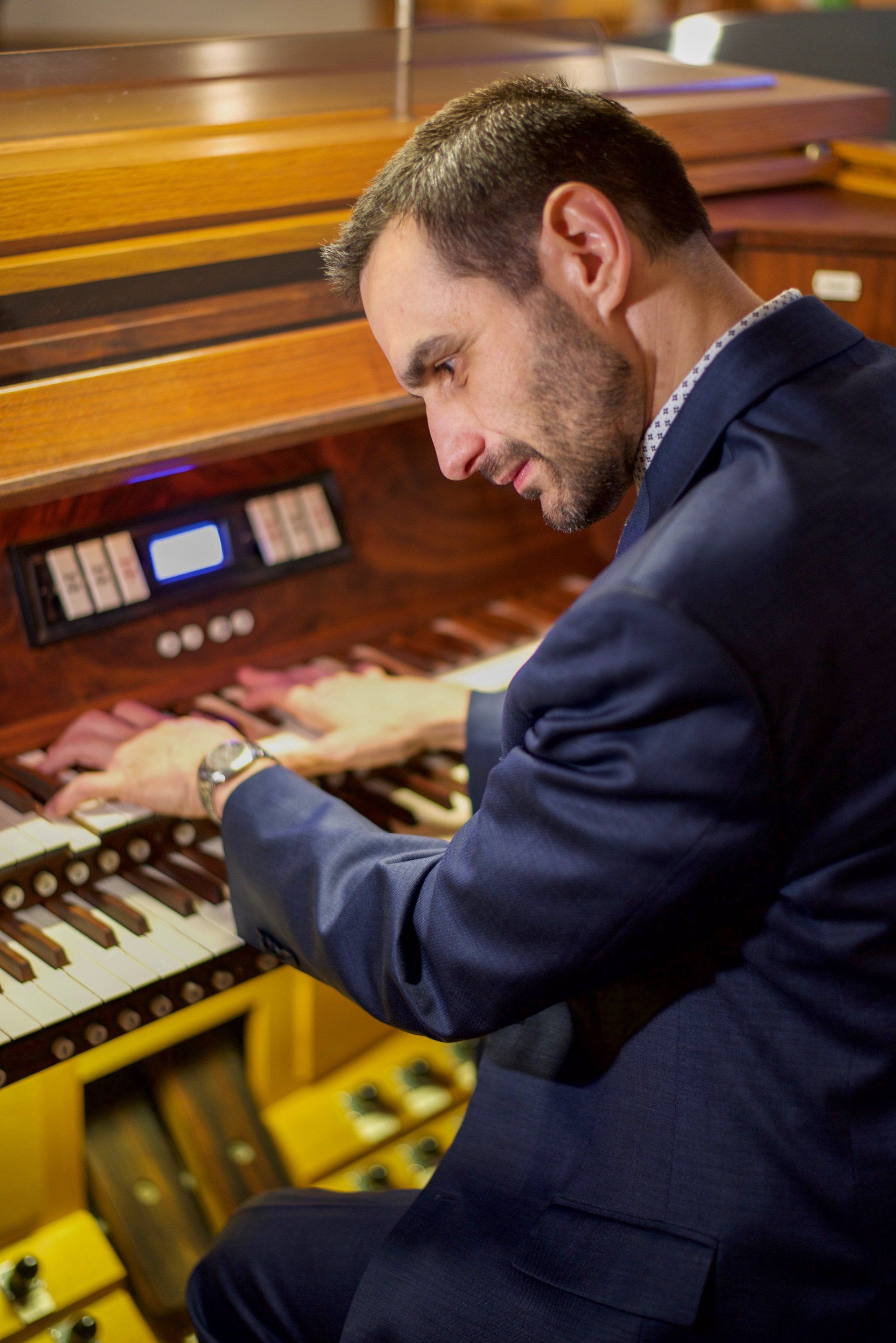 A man in a suit is playing an organ